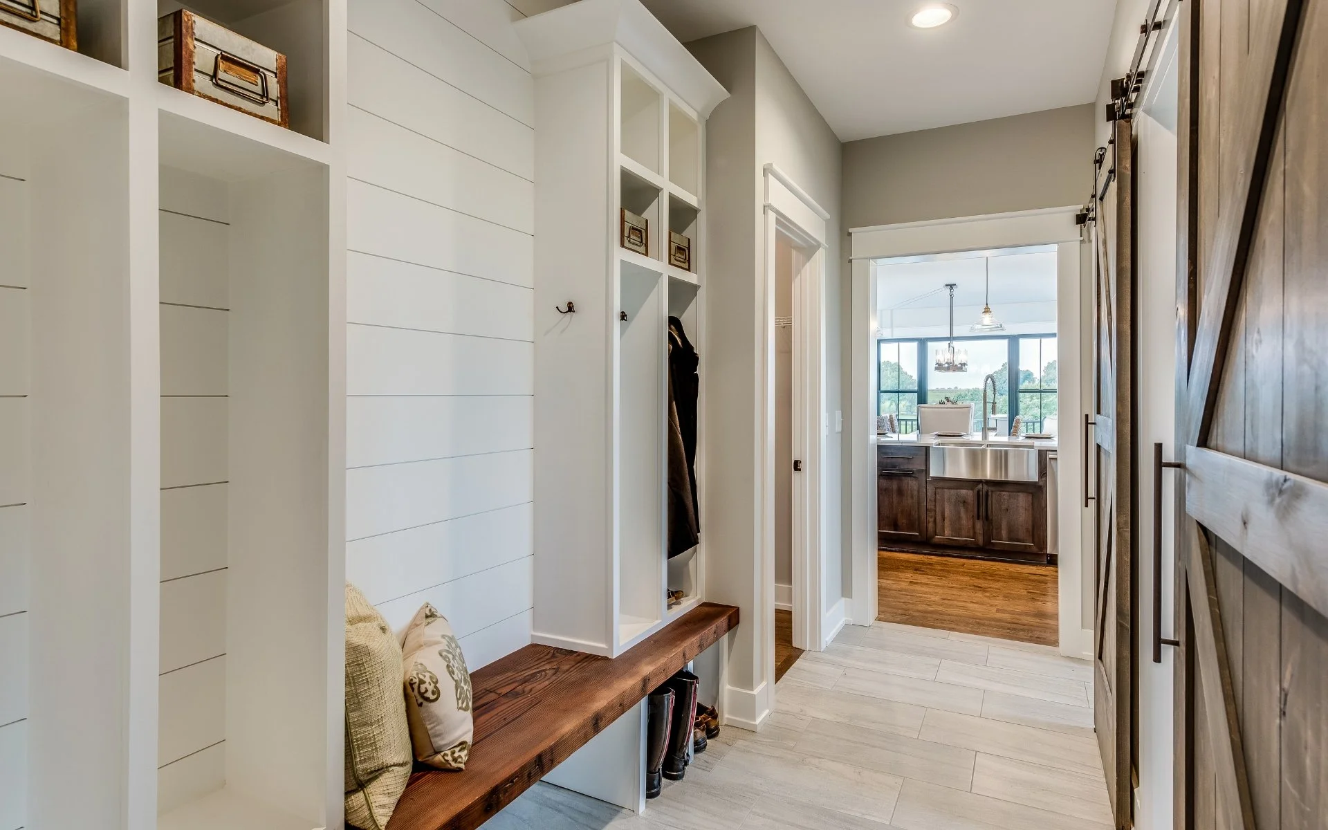 white custom mudroom with shiplap coat hooks and wood bench