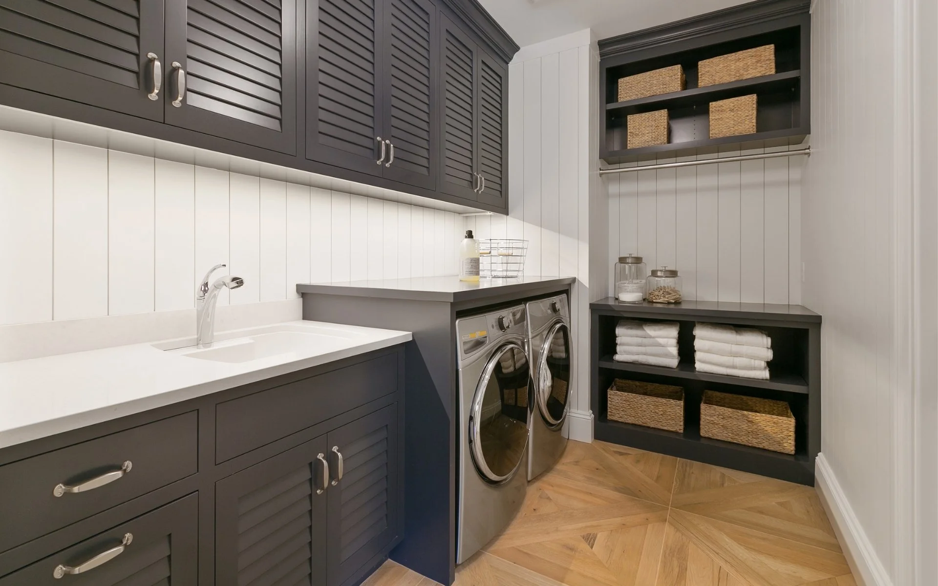custom white laundry room with gray cabinets hanging rack and folding table
