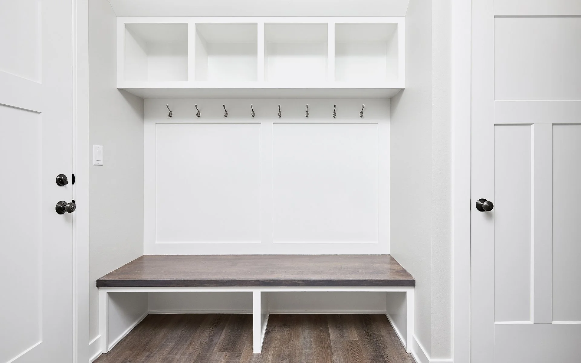 white custom mudroom with bench seating and coat hooks