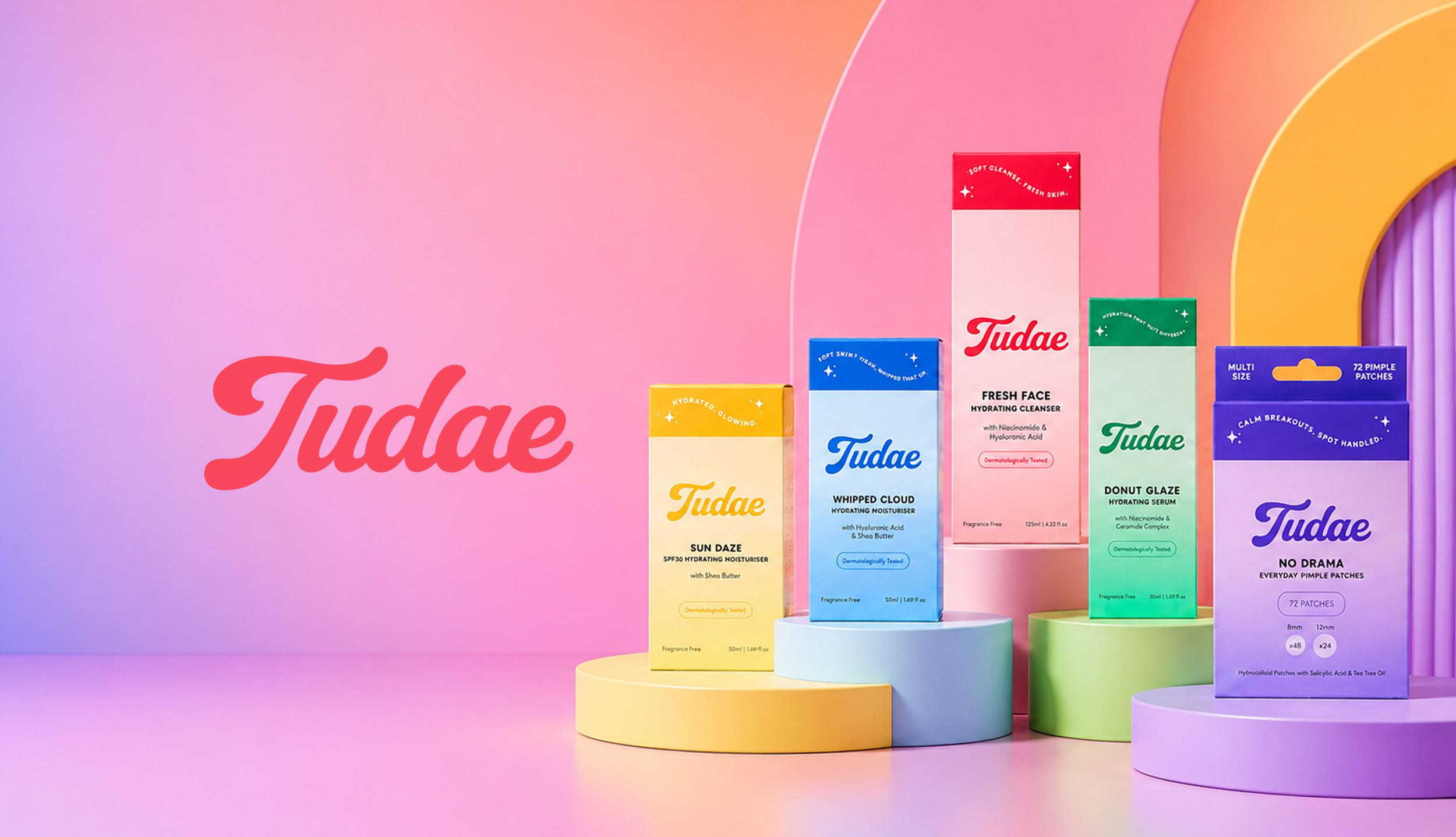 An array of skincare and cosmetic product boxes on colorful pedestals with a pastel background. The brand name 'Tudae' is visible on scaling packaging and the logo is in red cursive.