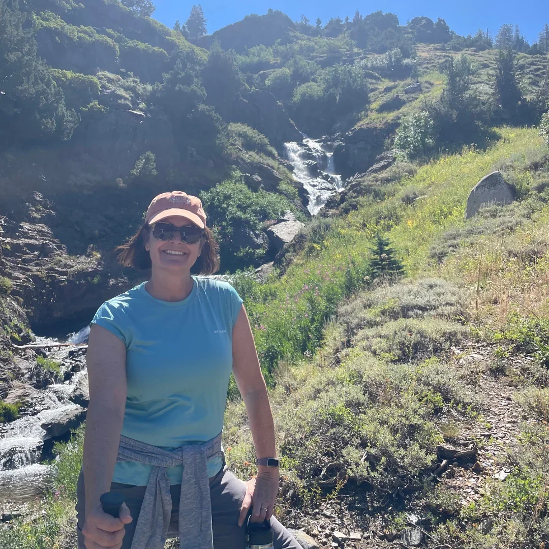 Ground Education's co-founder Holland Brown stands in front of a waterfall on a hike.