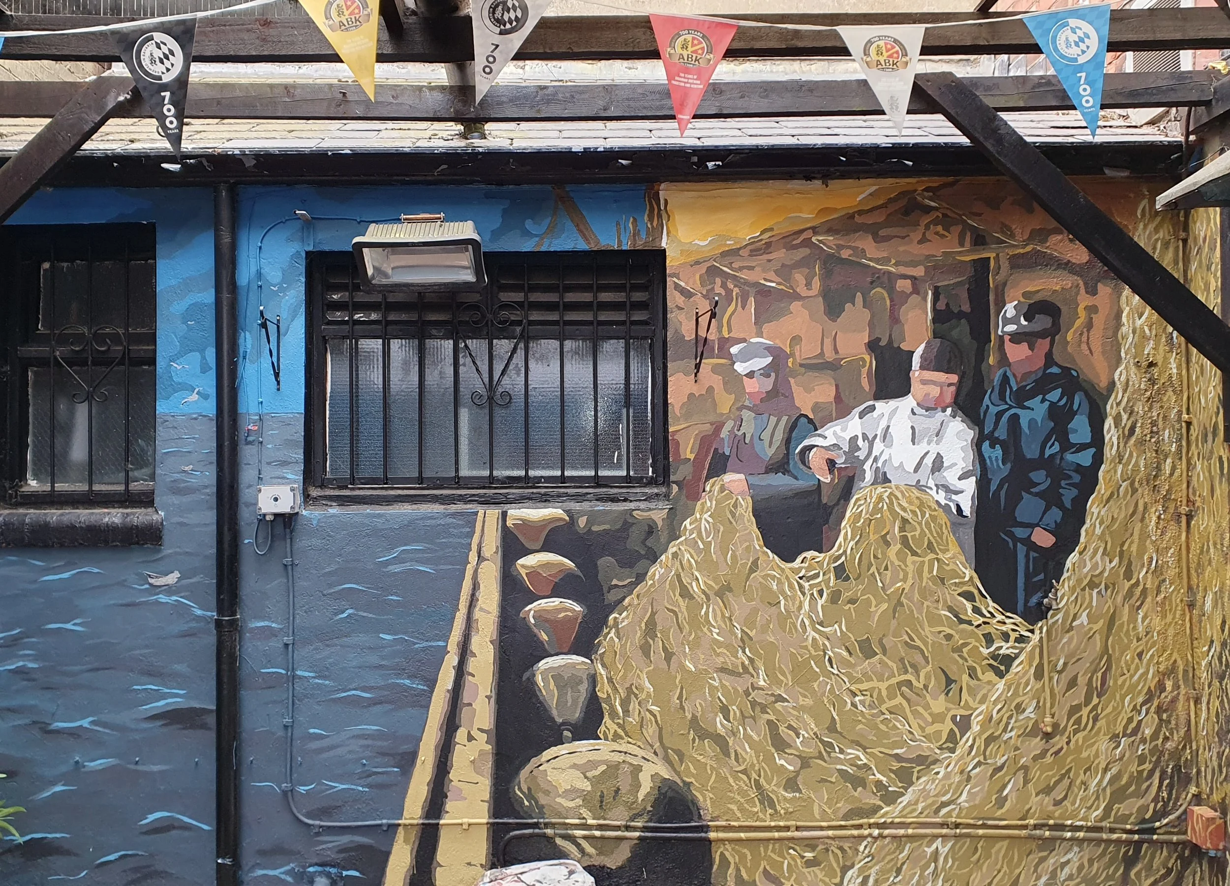 A mural featuring two police officers in uniform, standing in front of a landscape background, with colorful flags hanging above.