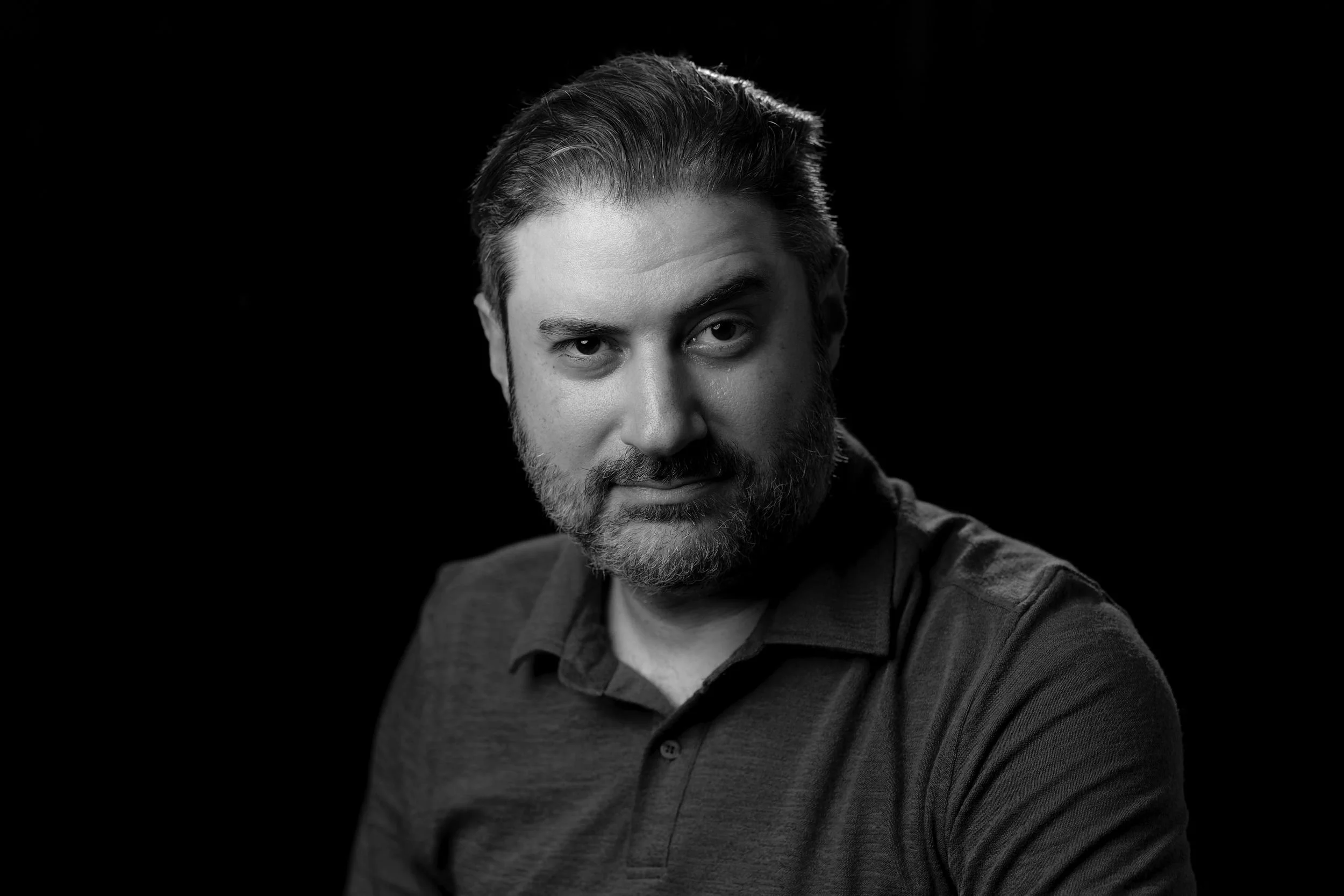 Black-and-white portrait of Eliyahu Ungar-Sargon against a dark background, looking directly at the camera.