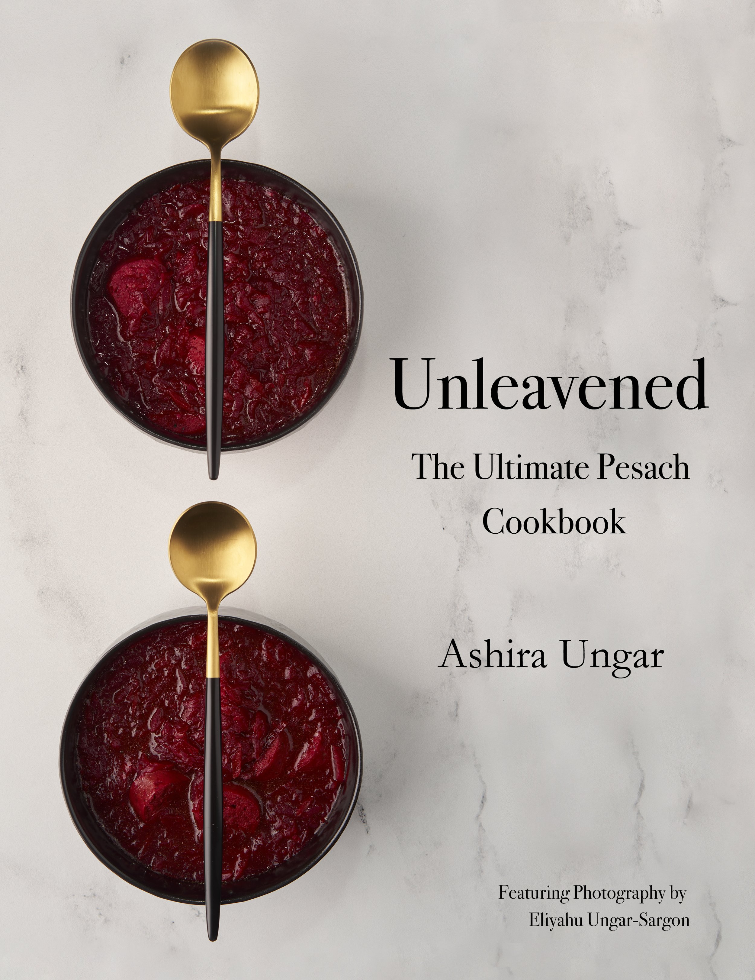 Cover of the cookbook Unleavened: a gold spoon resting in a dark bowl of deep red charoset on pale marble.