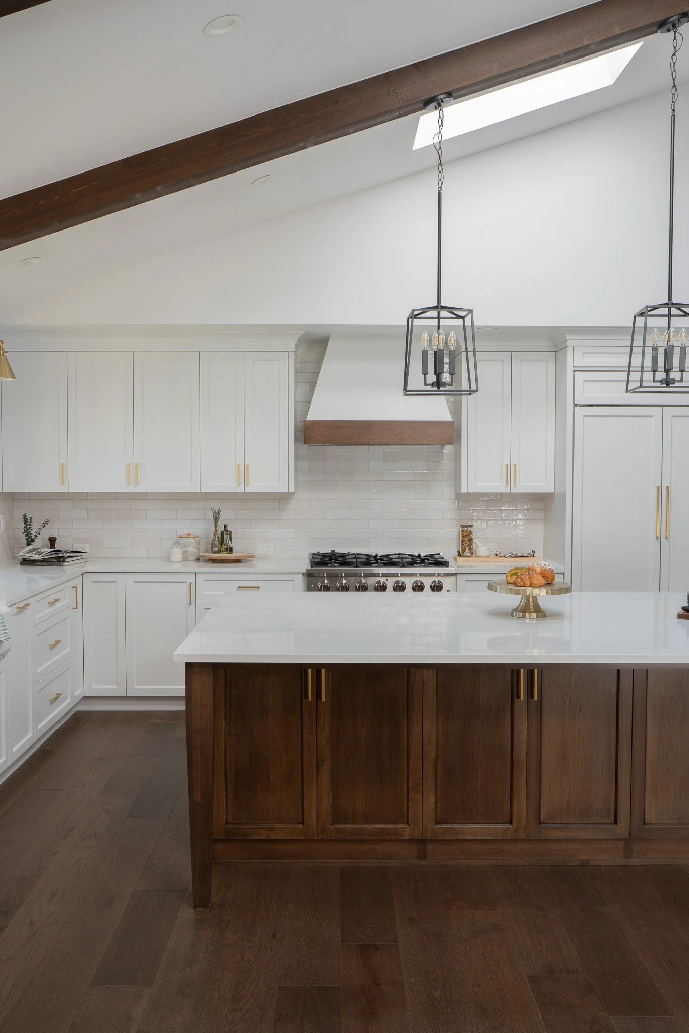 Modern kitchen with white cabinets, a wooden island, and overhead lighting fixtures.