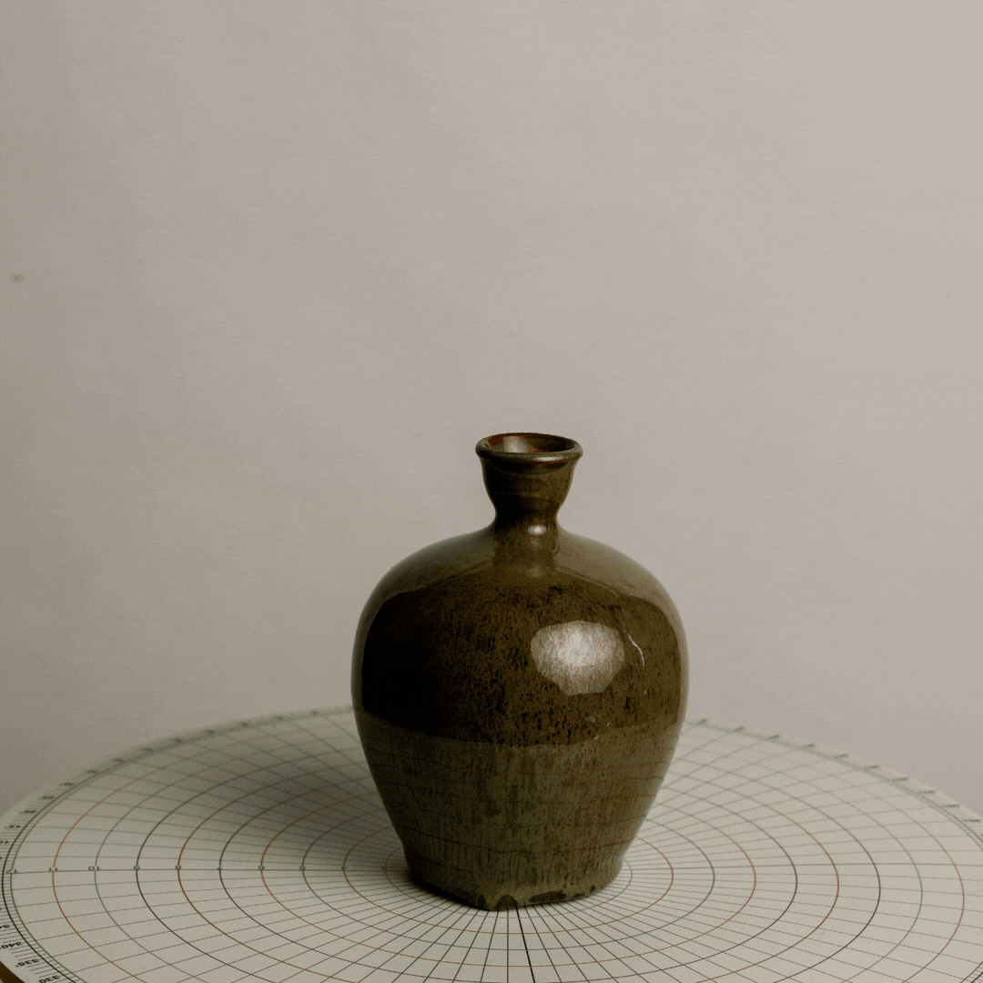 Brown ceramic vase on a circular grid surface.