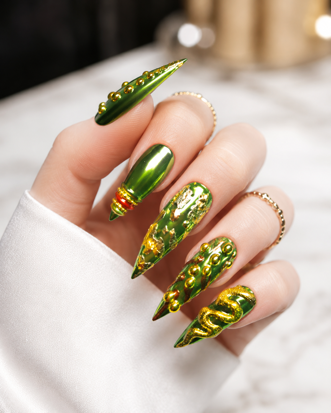Close-up of a hand with elaborately decorated long green nails featuring gold accents and 3D embellishments.