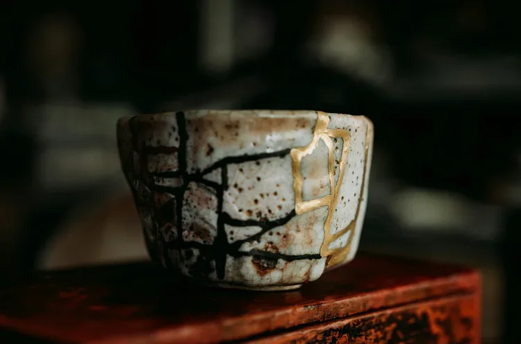 A ceramic bowl with a crackled glaze and gold accents, sitting on a wooden surface.