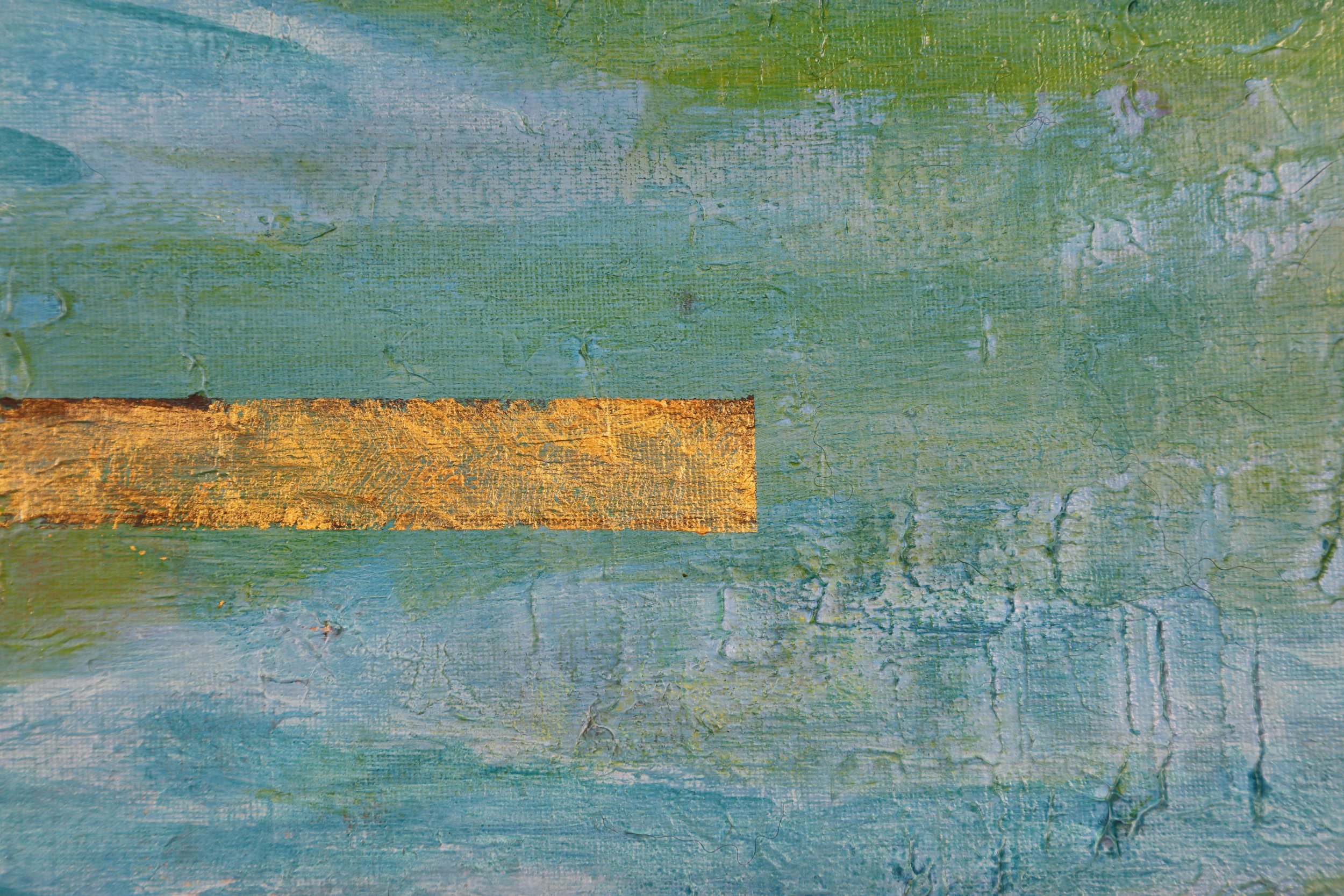 Close-up of painted wooden surface with blue and green hues and a horizontal strip of gold paint.