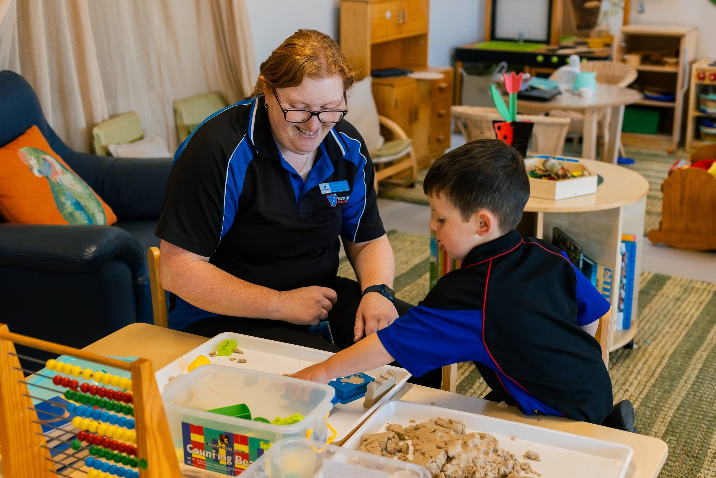 A teacher playing with a young student in a classroom at Emmanuel Christian School