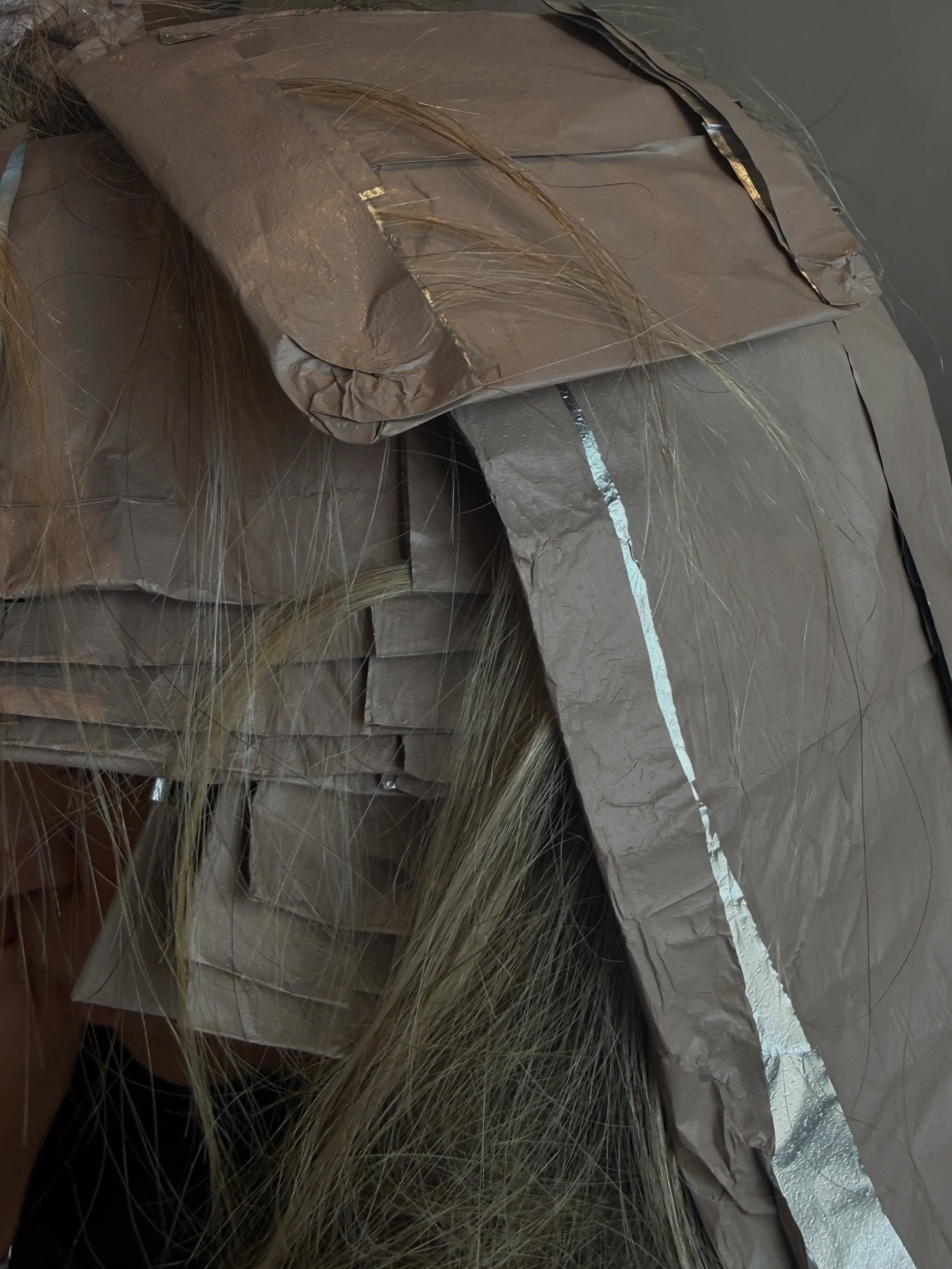 Close-up photo of a brown paper bag with spaghetti noodles spilling out of it, on a reflective surface.