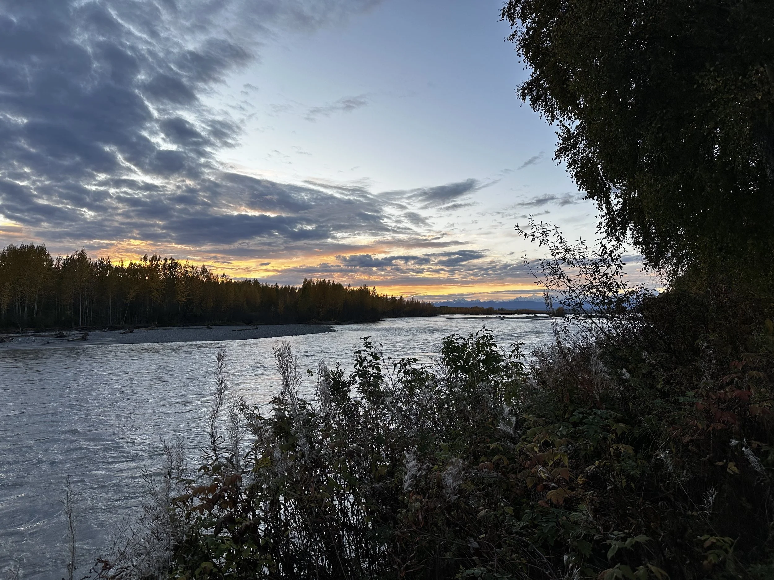 Sunset over the Susitna River in Talkeetna, Alaska, with pink and orange sky reflecting on the water