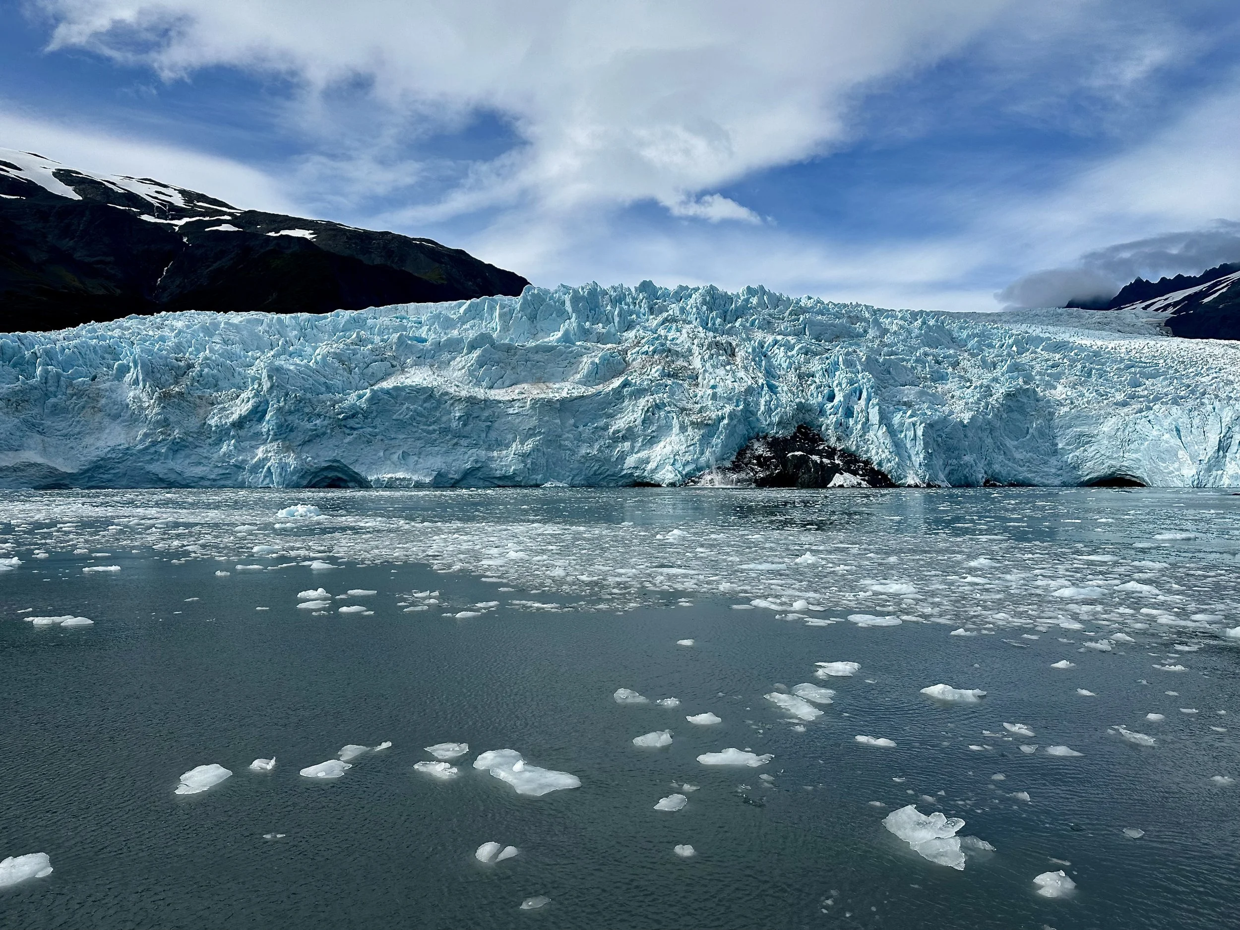 Close-up of a blue glacier face with floating ice chunks in the water at Kenai Fjords National Park, Alaska