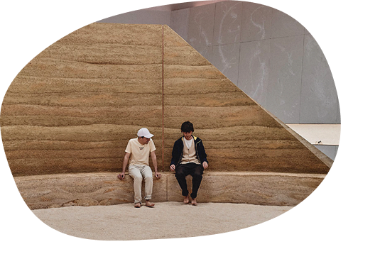 HOME, Venice Biennale: two people sitting on the curved rammed earth bench inside the Australia Pavilion