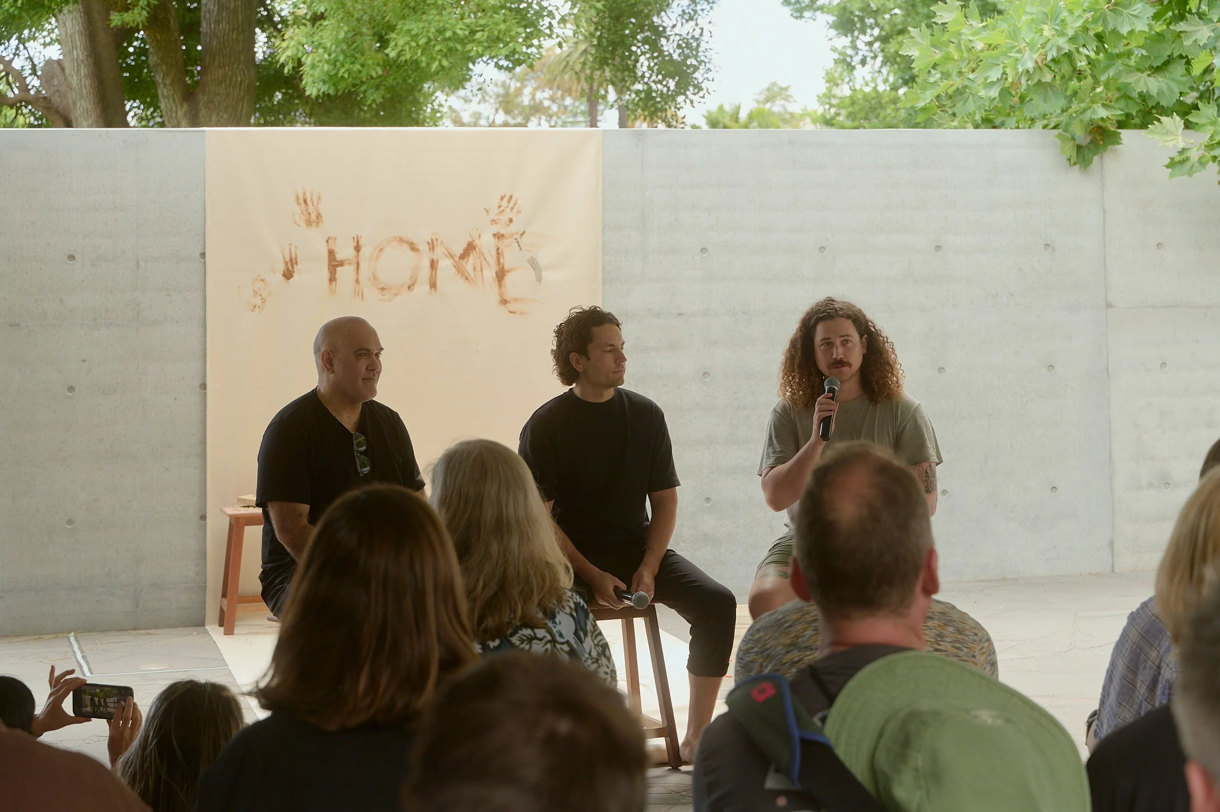 Audience listening to a conversation beneath a hanging banner reading "Home"