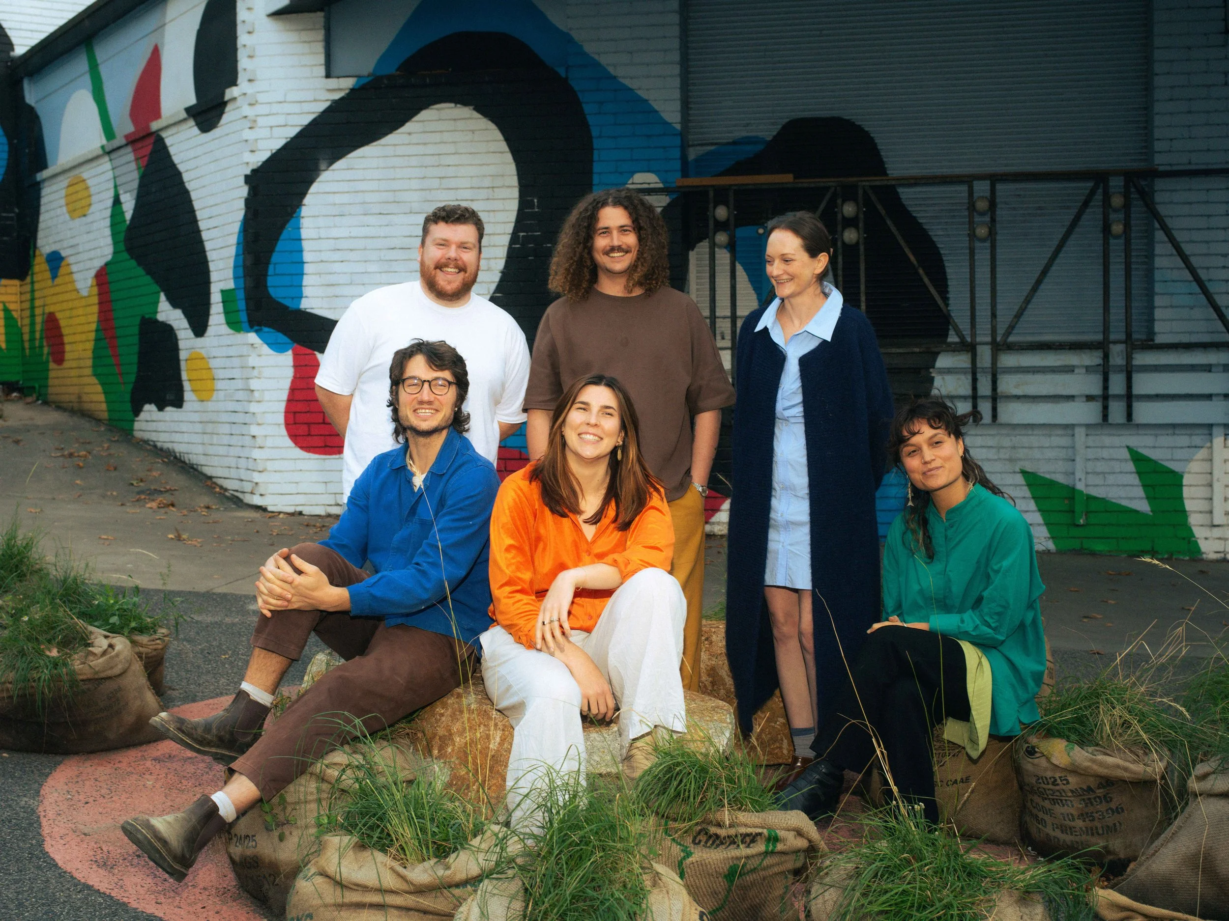 The Winsor Kerr team in front of a painted mural. Standing, from left: Matt O'Connor, Bradley Kerr, Edwina Thomson. Seated: Almo Troup, Shannon Winsor, Eleni Timoteo.