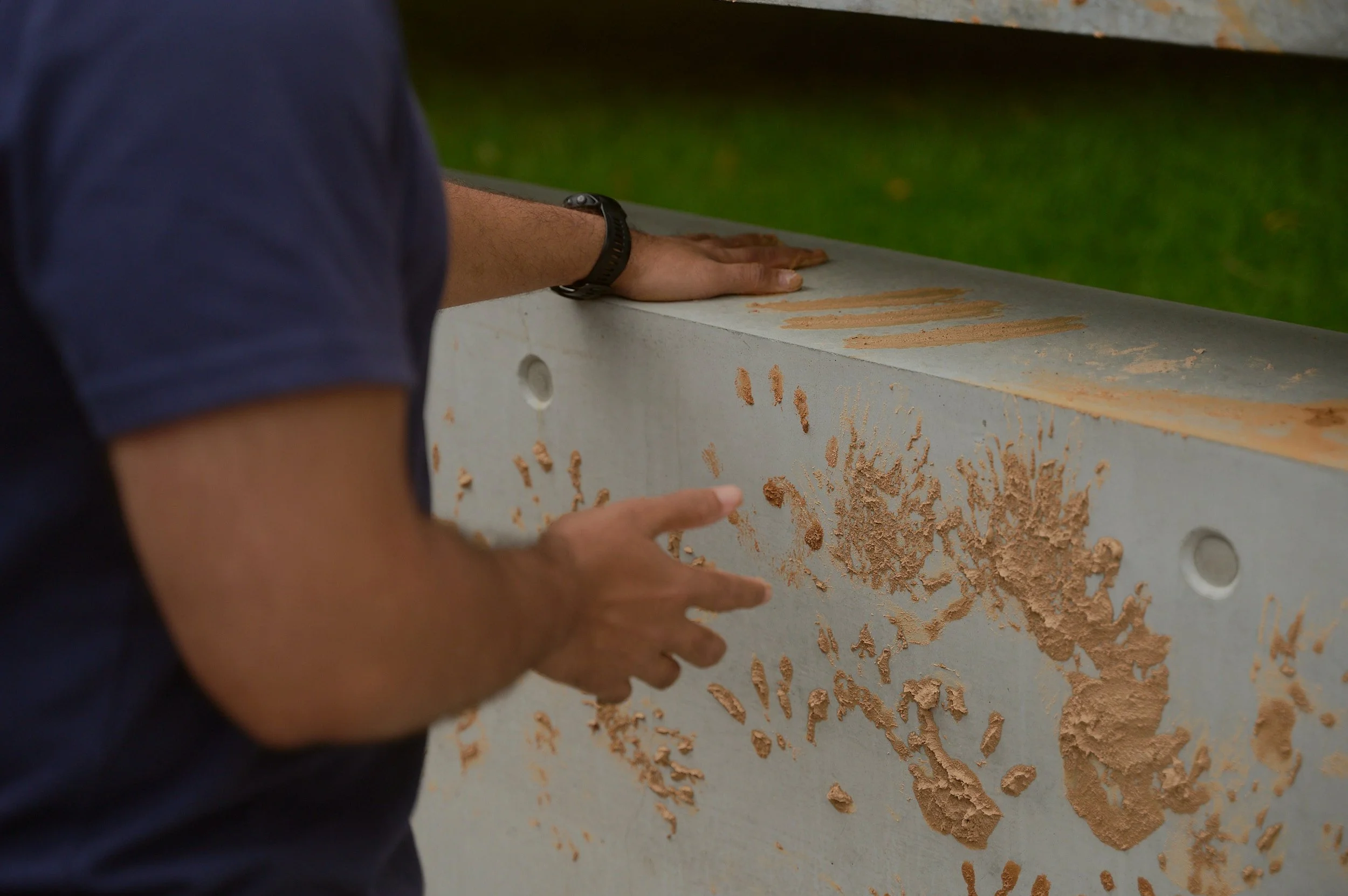 A visitor pressing his ochre-covered hand onto the concrete wall to add his print among the others