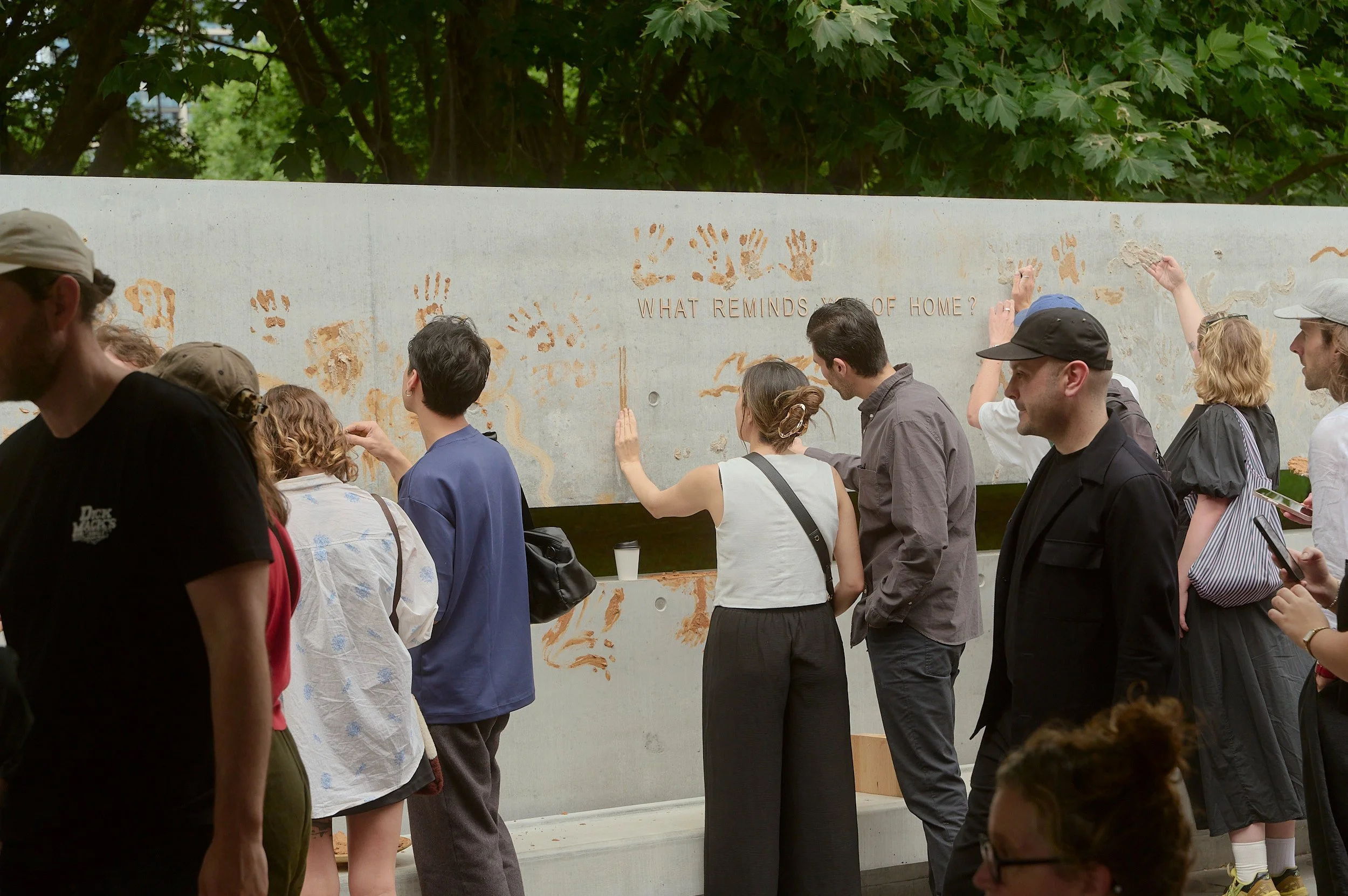 Visitors gathering along the concrete wall, adding their own ochre marks