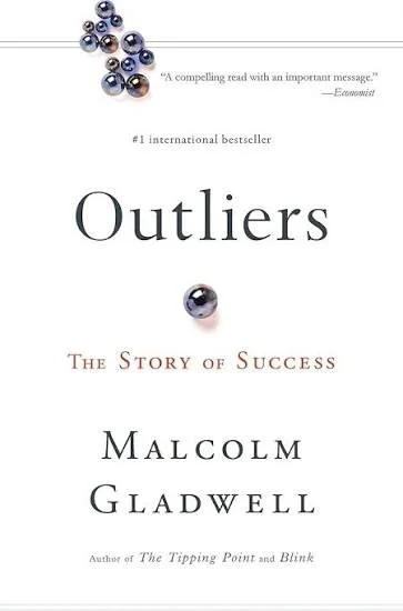 Book cover of 'Outliers: The Story of Success' by Malcolm Gladwell, featuring a white background with scattered metallic balls and a single ball below the title.