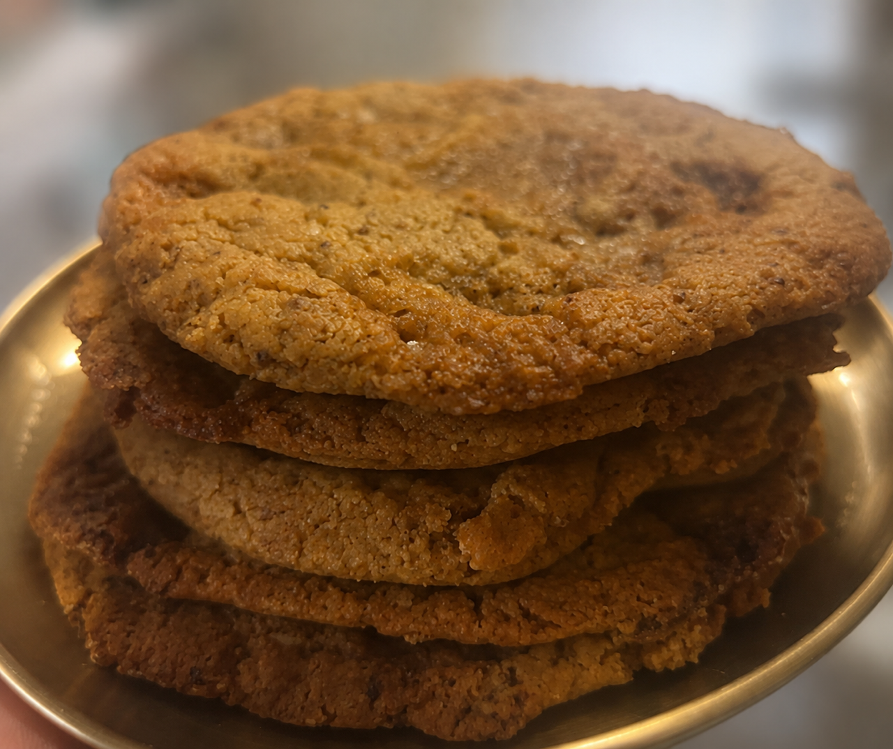 Close-up of a stack of four chocolate chip cookies on a gold-colored plate.