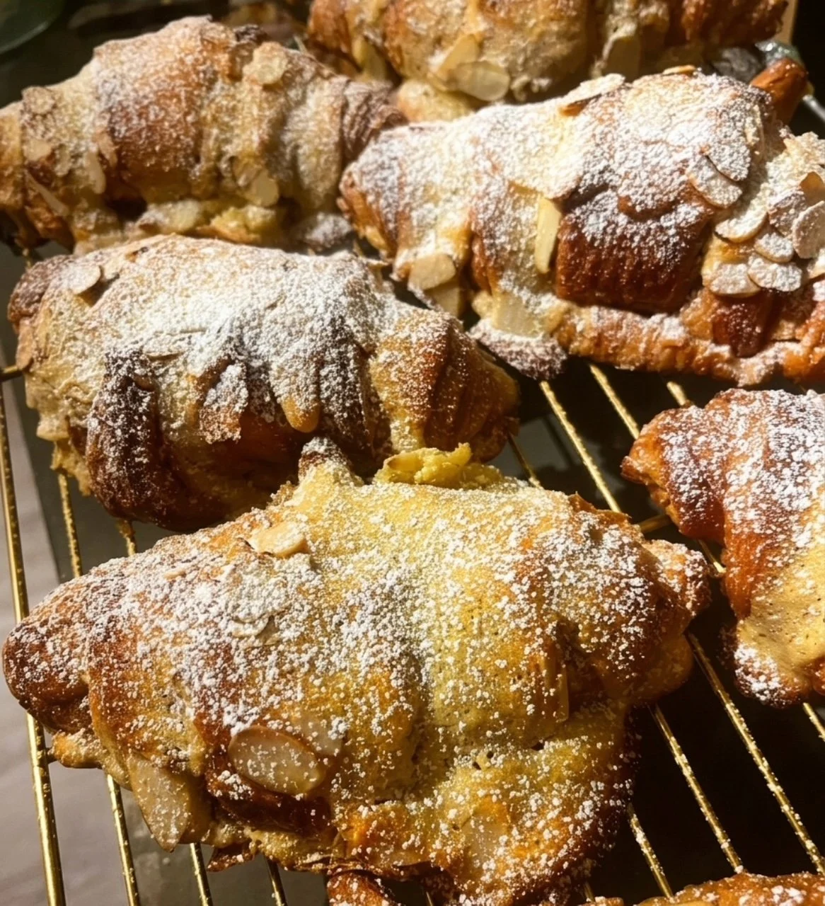 Dusted baked almond pastries on a cooling rack.