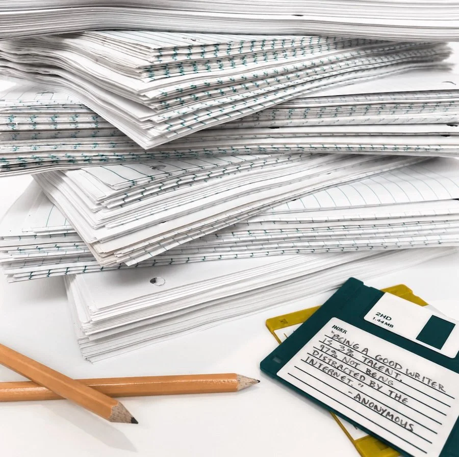 Stack of notebooks, floppy disks, a pencil, and several sheets of paper.