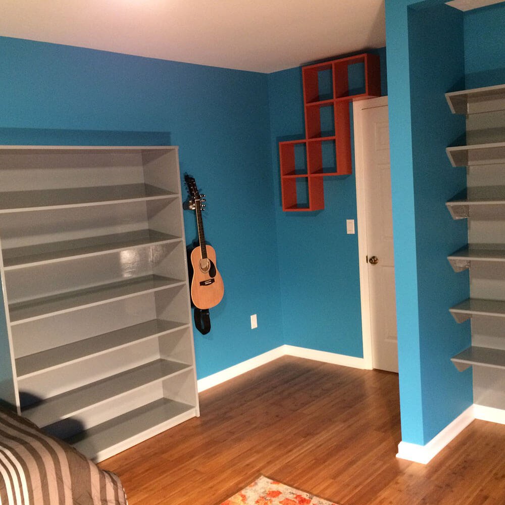 Room with blue walls, wooden shelves, guitar hanging on the wall, and a closed white door.