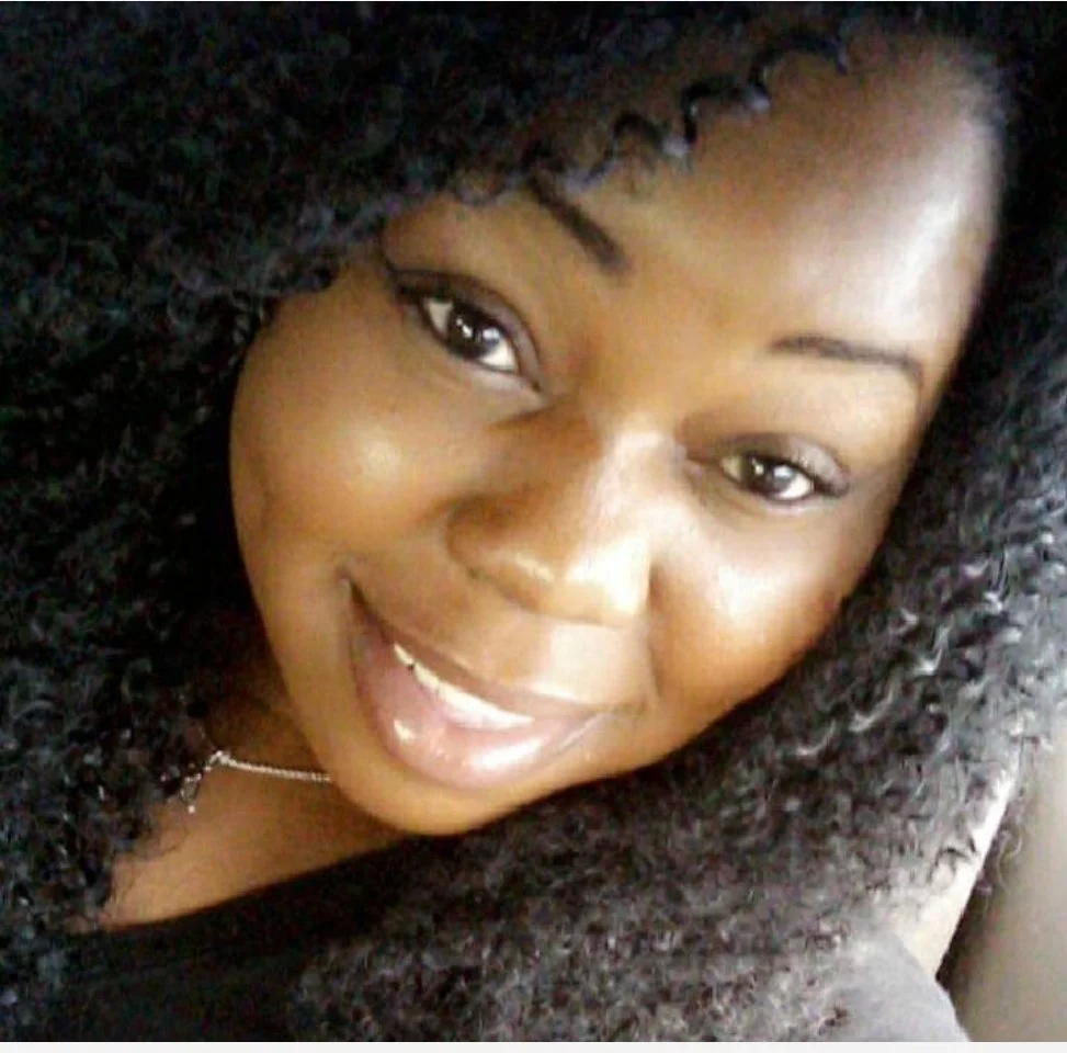 A woman with curly black hair smiling at the camera.