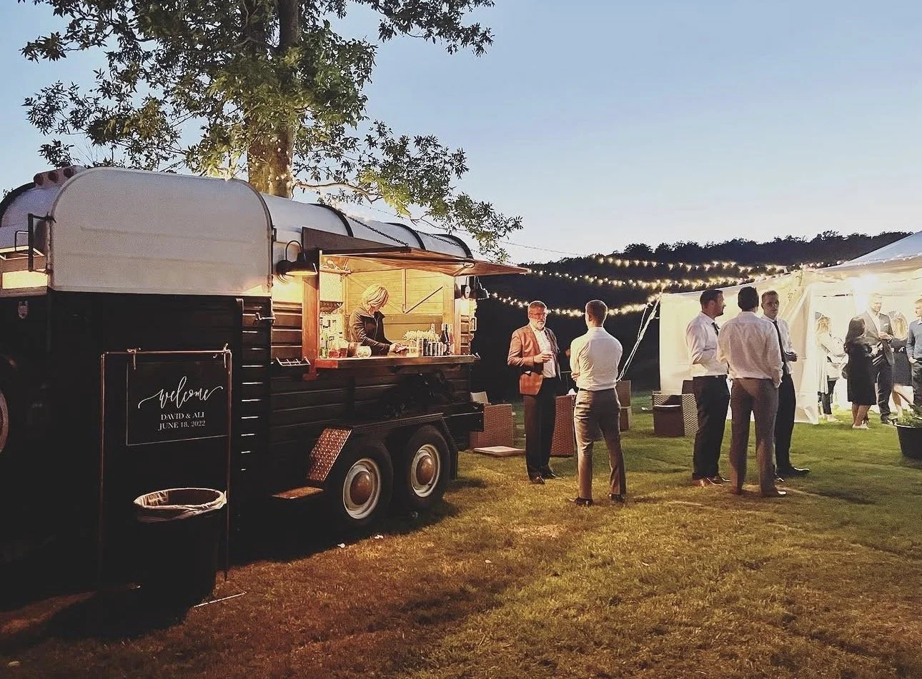 Vintage bar trailer decorated and lit up for an evening reception.