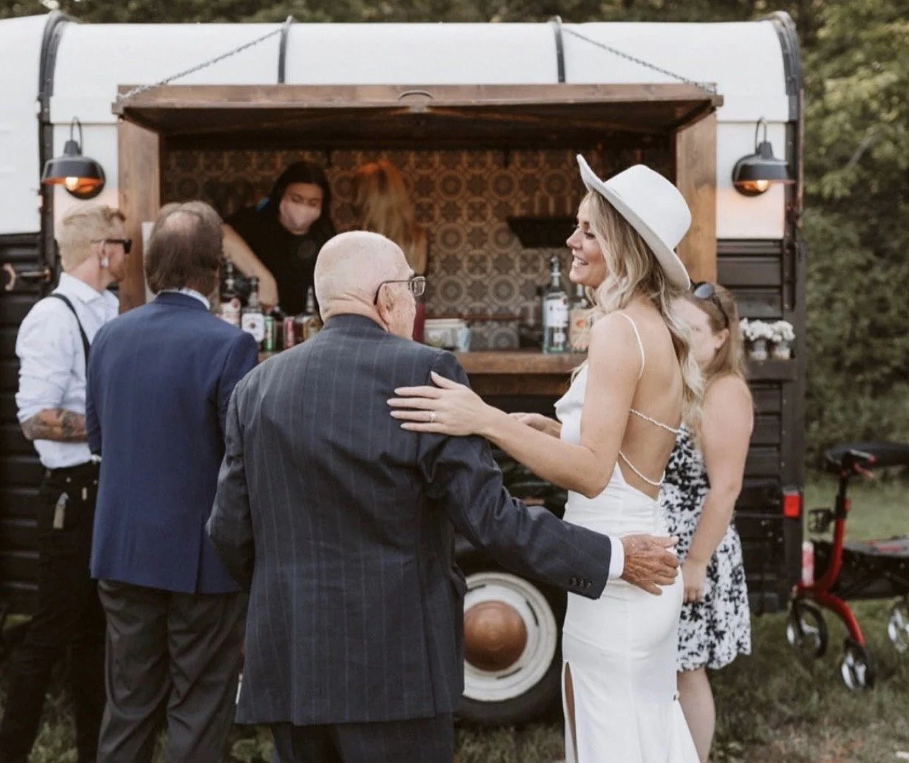 Bride and father of the bride embracing in front of Amora's mobile bar.