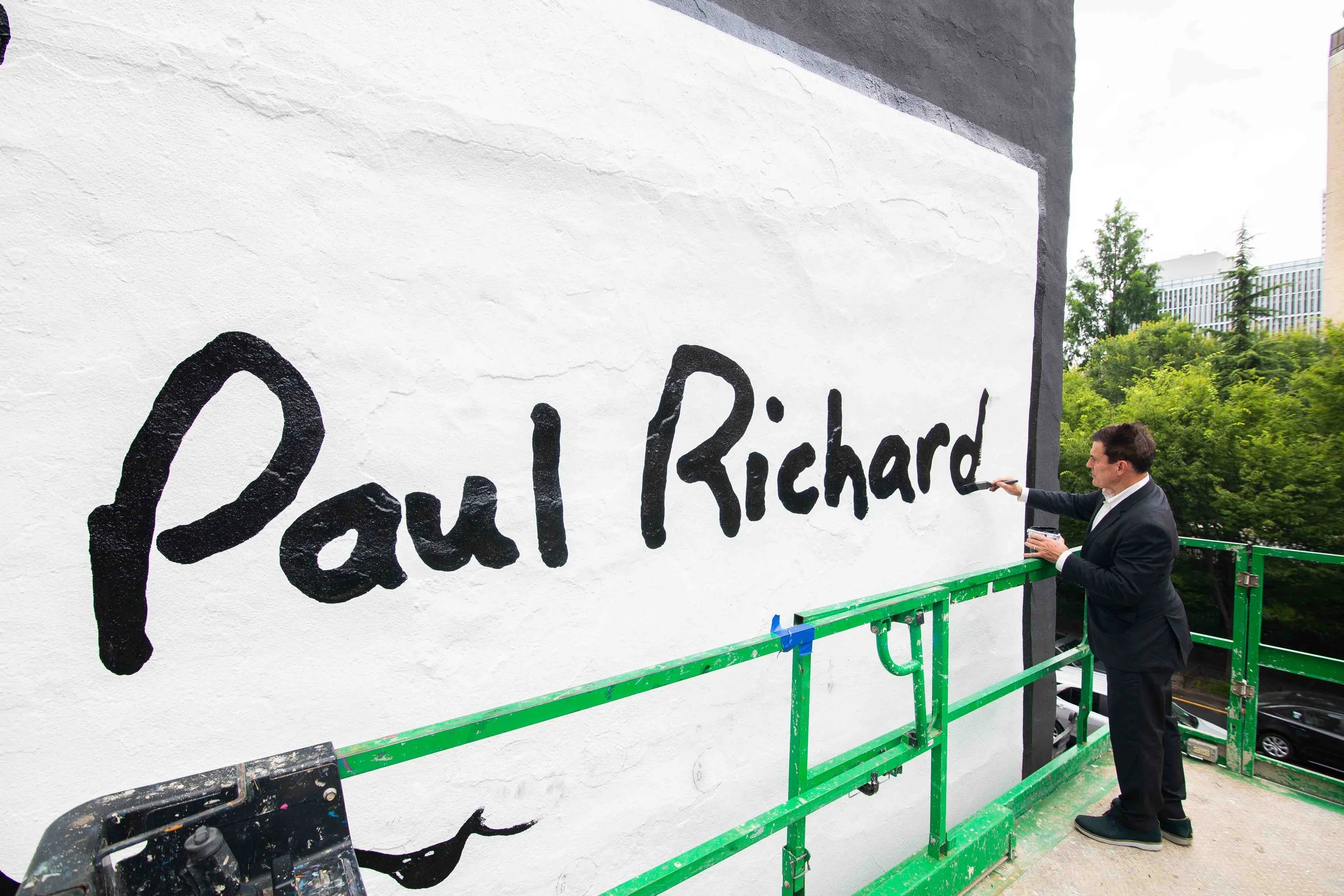 Paul Richard painting wall on cherry picker