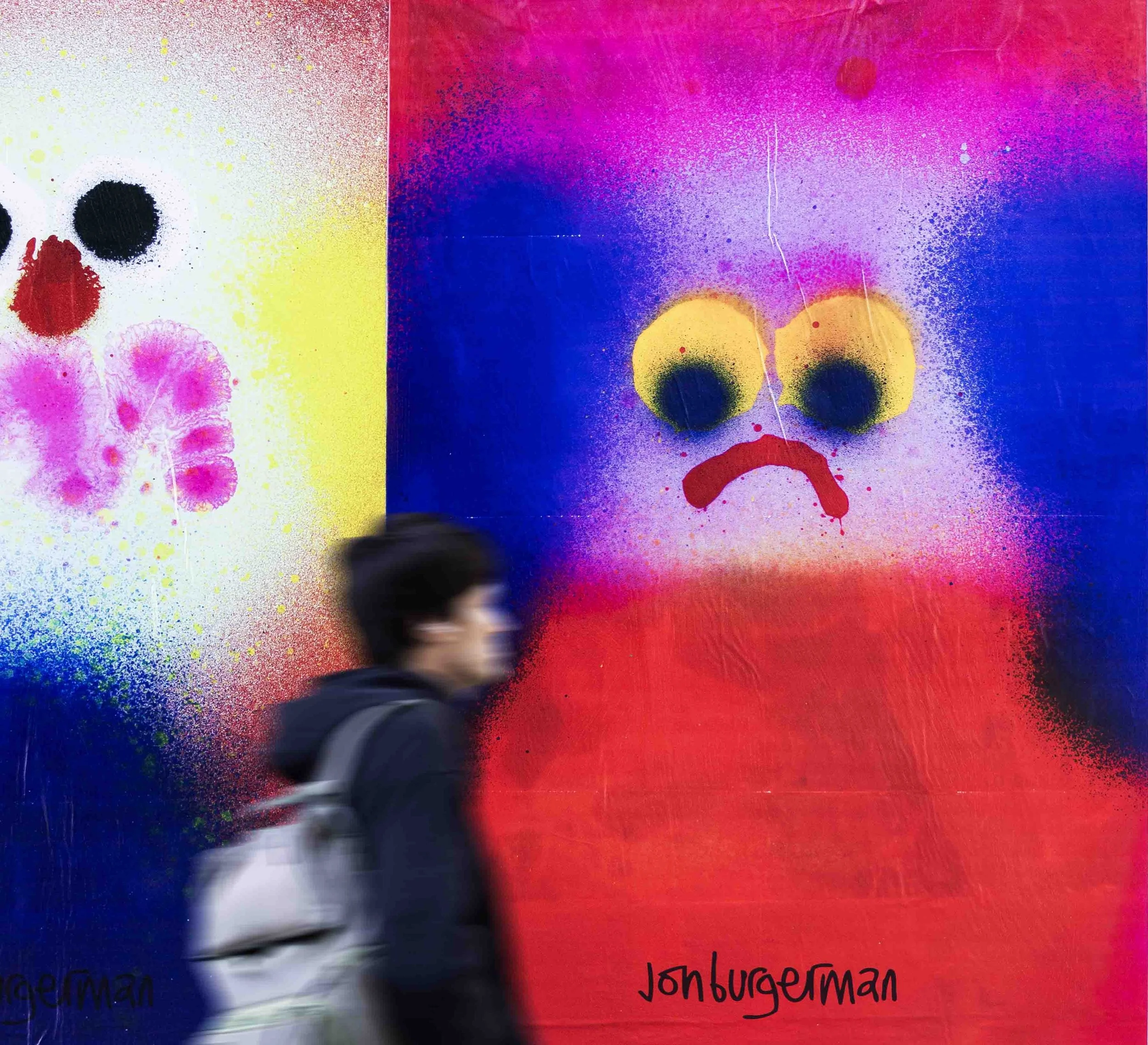 man walking in front of jon burgerman art poster