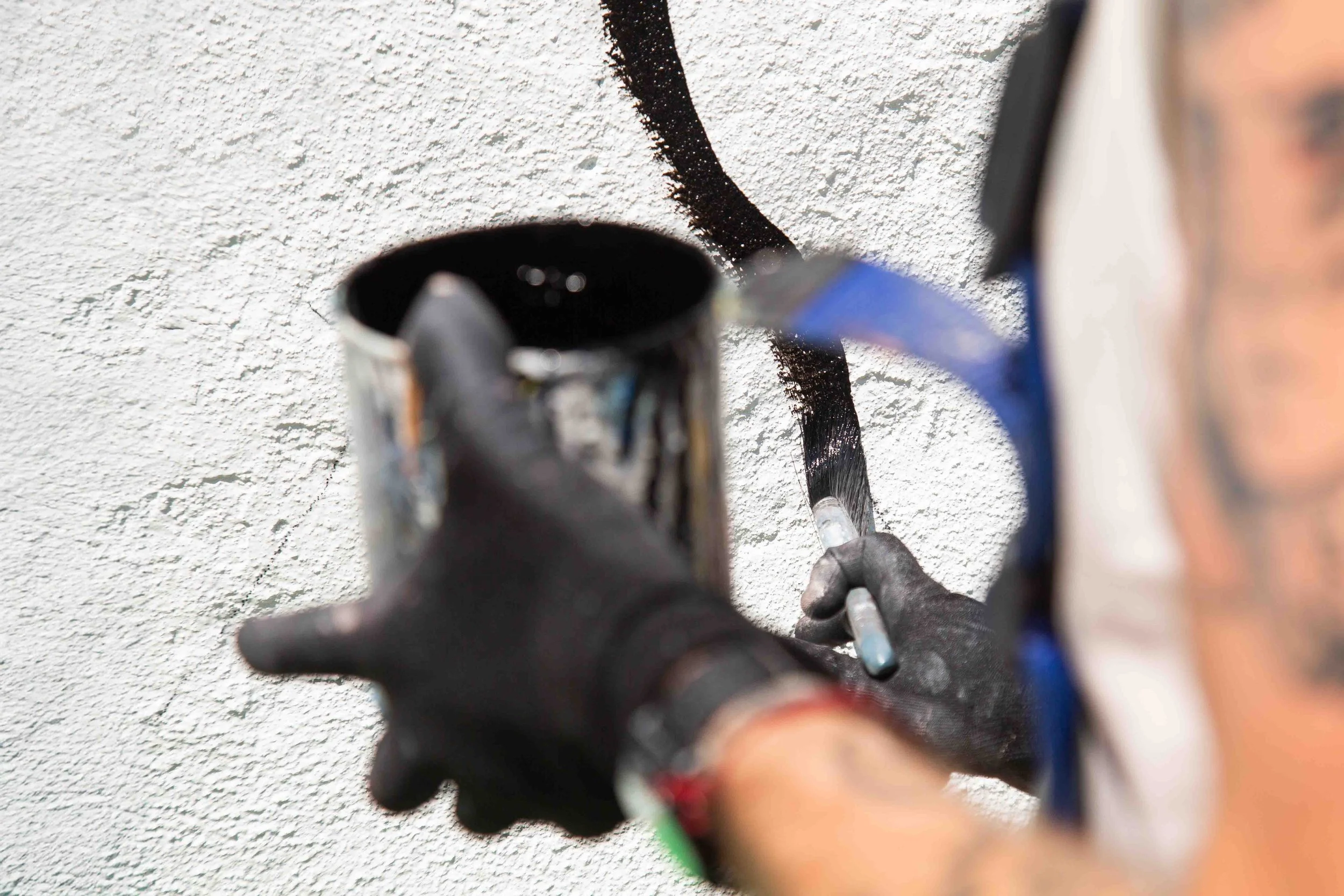 holding paint can and painting wall