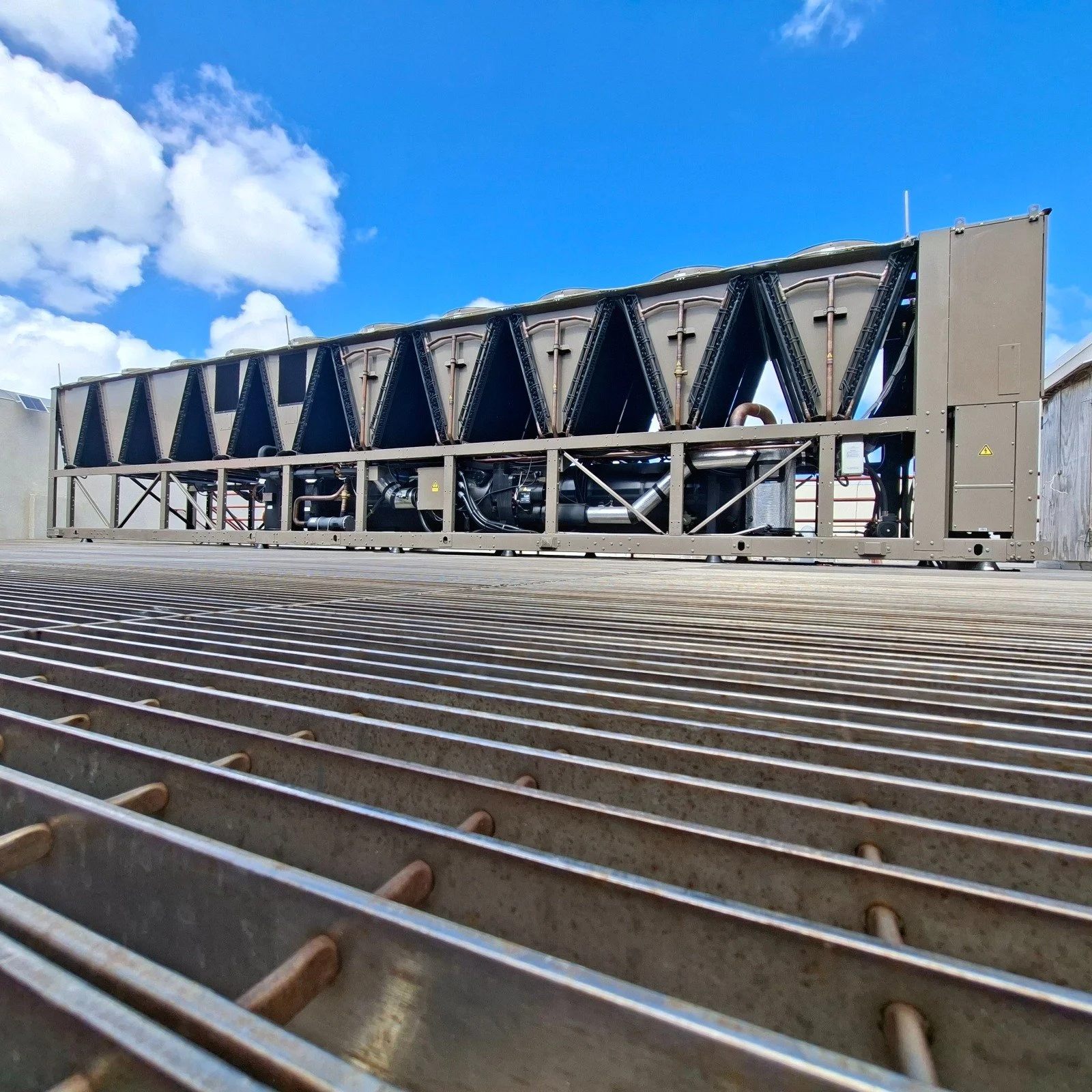 Un equipo de refrigeración grande instalado en una azotea, con cielo azul y nubes. Soluciones HVAC.