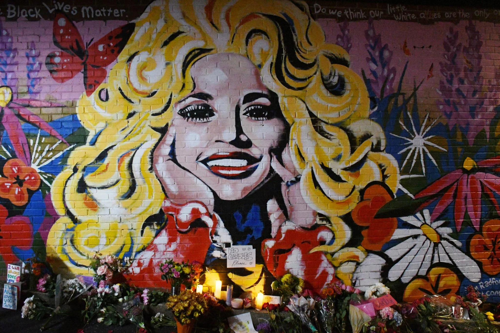 Dolly Parton mural in Nashville, Tennessee, surrounded by flowers left in her memory following her passing.