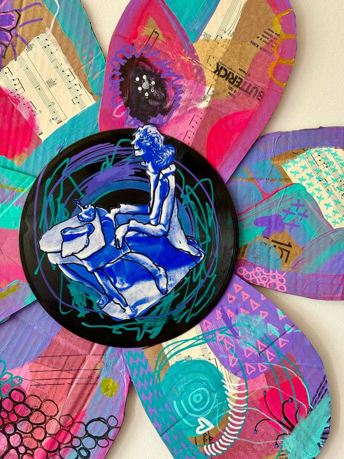 Colorful mixed media art featuring painted butterflies made from paper and a painted record with a figure of a person sitting on a rock.