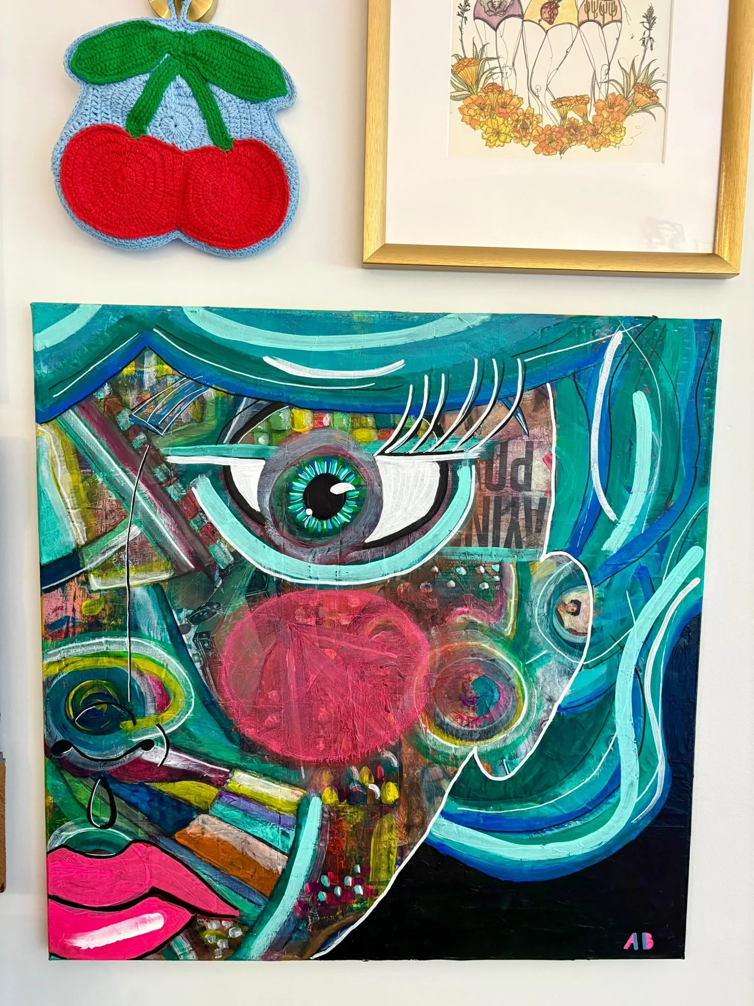 A colorful painting of a human eye with abstract patterns and vibrant colors, with a large pink circle in the background. The artwork has swirling lines and bold strokes, with a small signature in the bottom right corner that reads "AB."