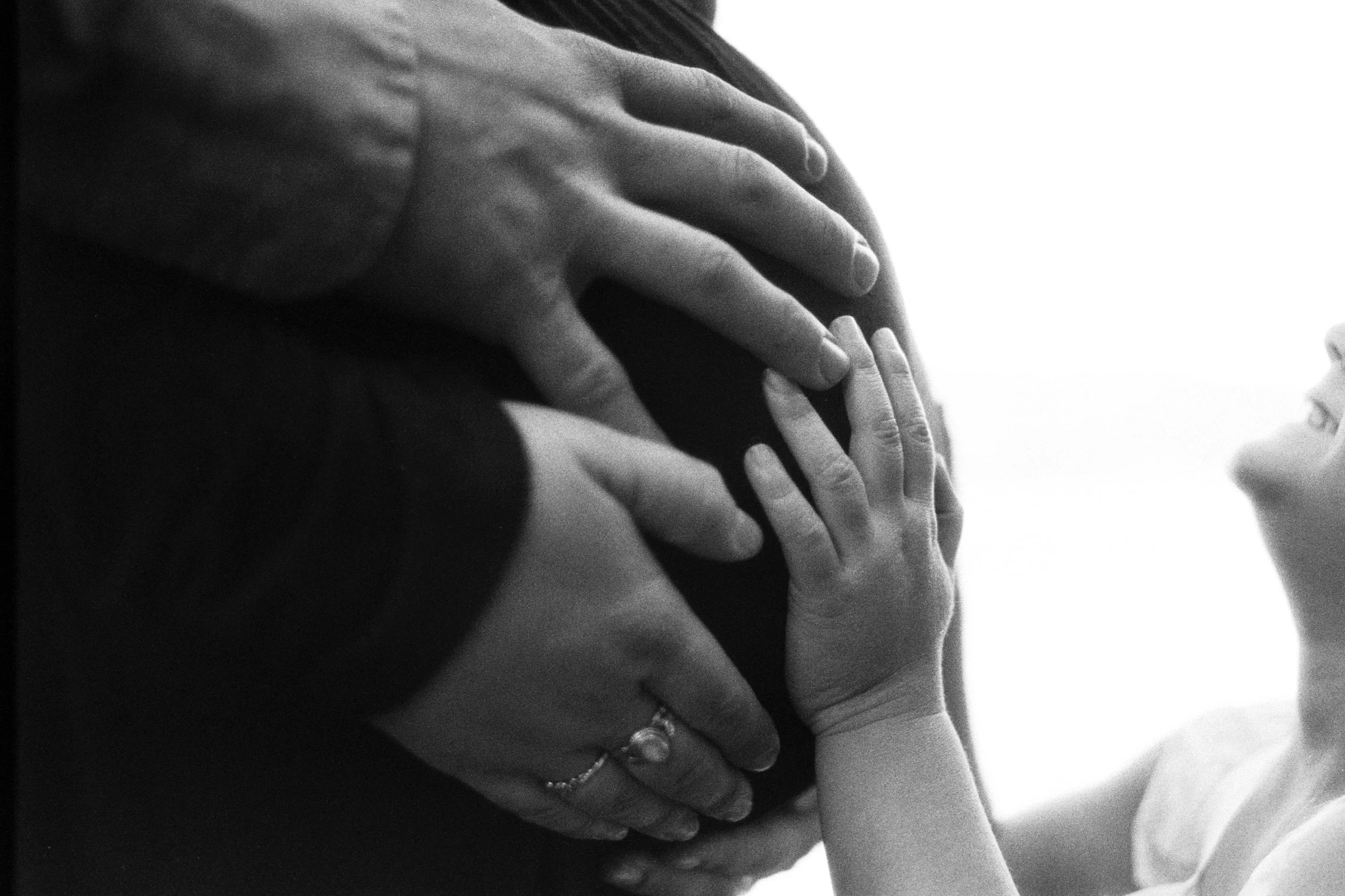 Close-up of two hands gently touching, one adult and one child's hand, in black and white.