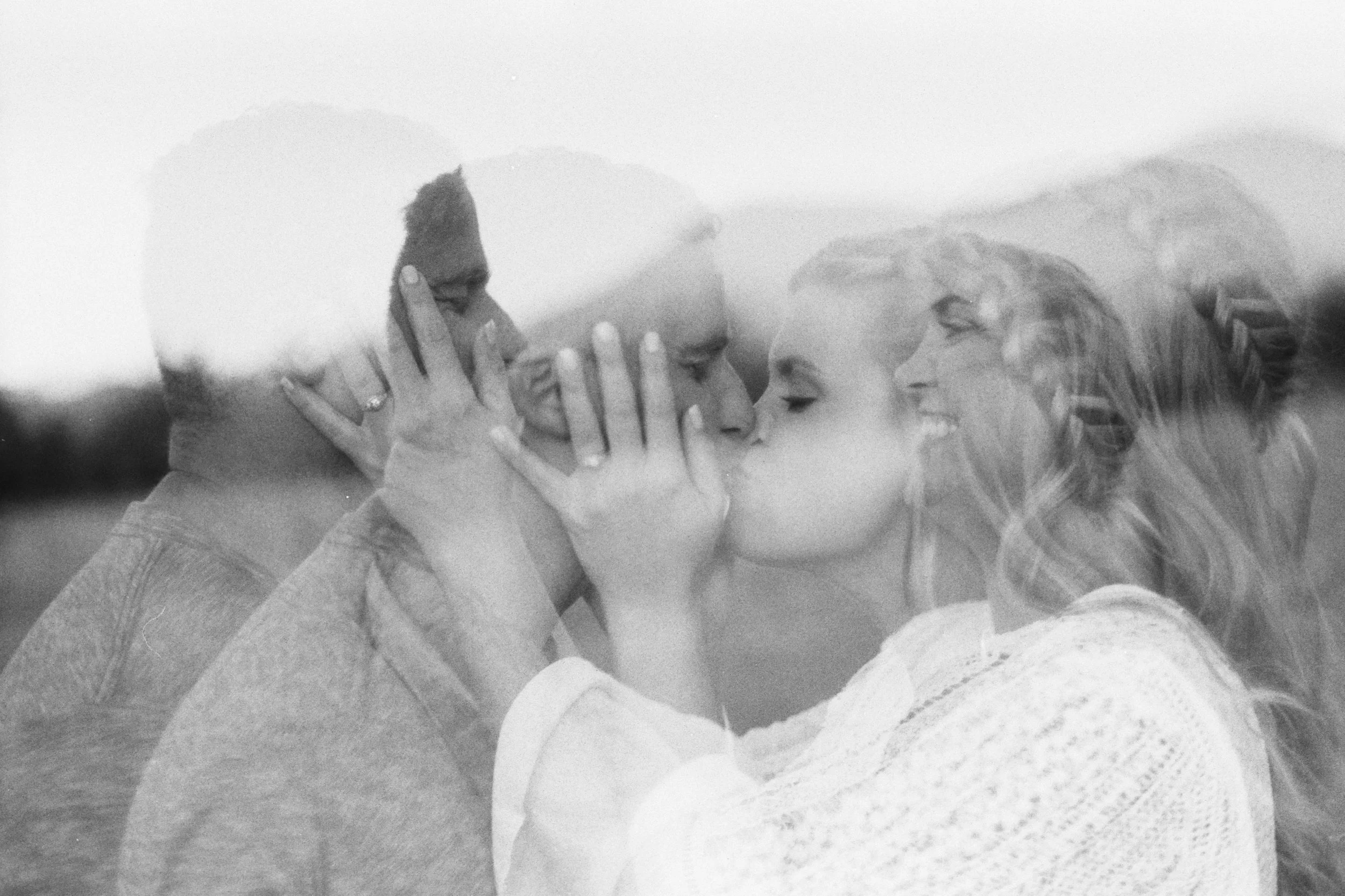 Two women with blonde hair smiling and touching foreheads in a close, intimate moment.