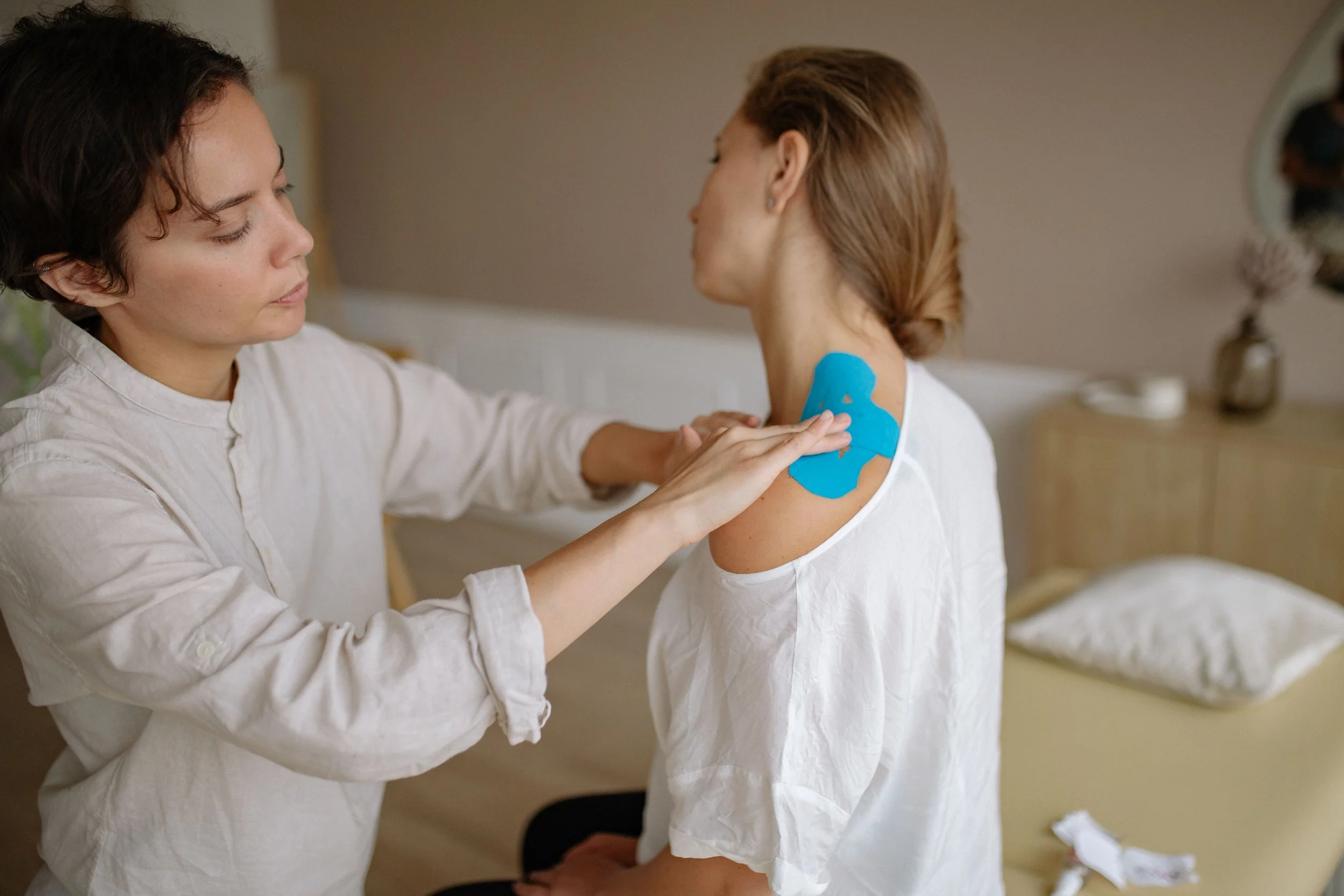 A healthcare professional applies a blue medical adhesive bandage to a patient's upper arm.