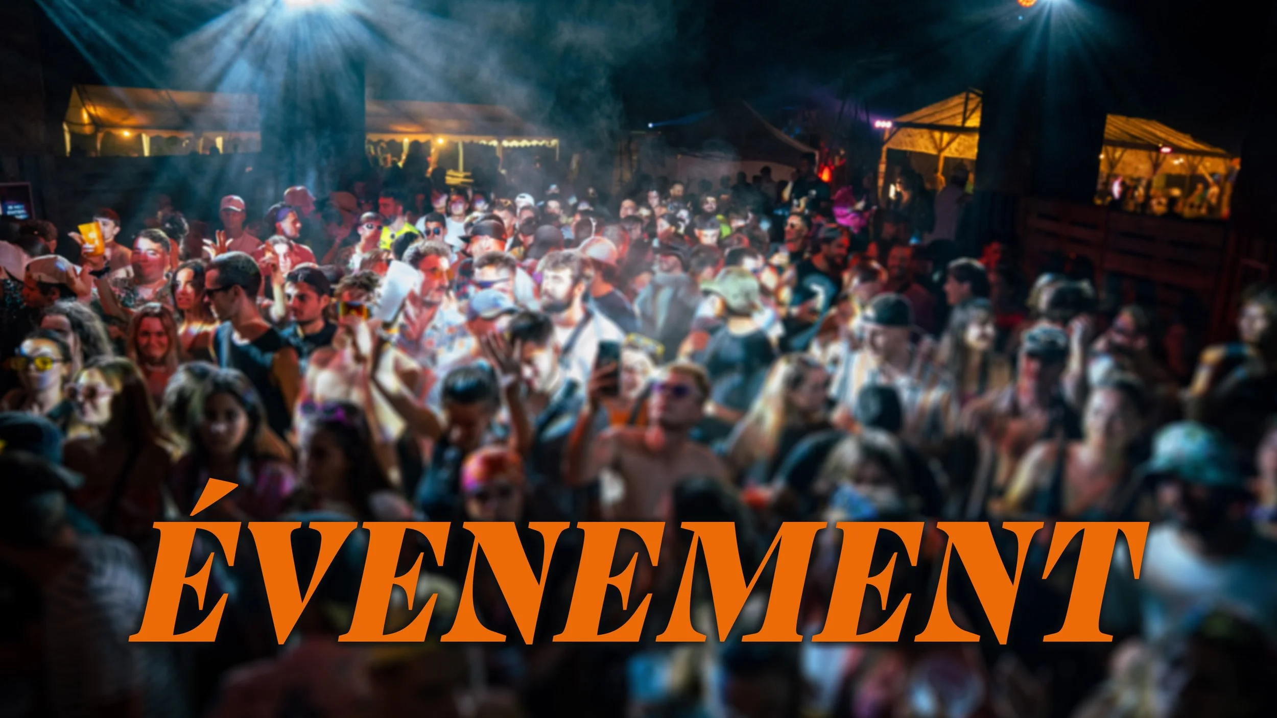 Une grande foule de personnes réunies lors d'un événement en soirée, sous des lumières colorées, autour de stands et d'une scène de festival.