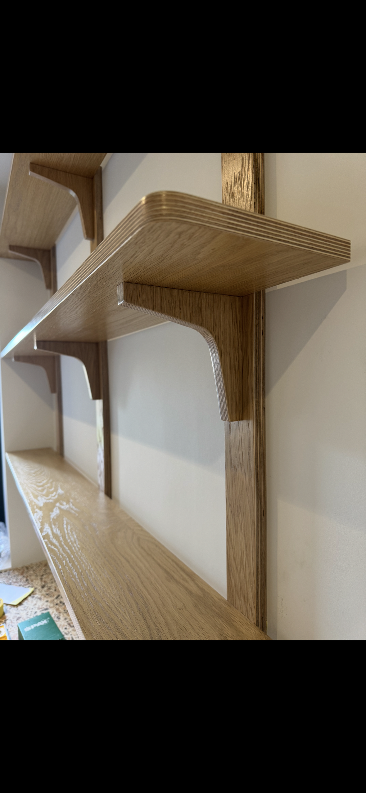 Close-up of a wooden wall-mounted bookshelf with multiple shelves, made of light-colored wood.
