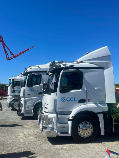 Multiple white semi-trucks parked outdoors under a clear blue sky.