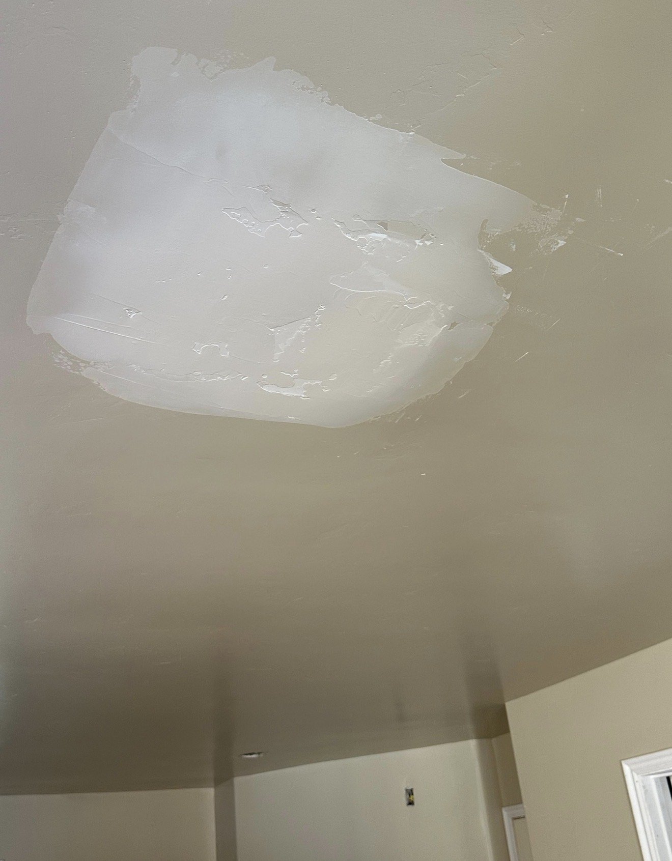 Ceiling with an area of missing paint or drywall patch, and interior walls with visible outlets and a door frame.