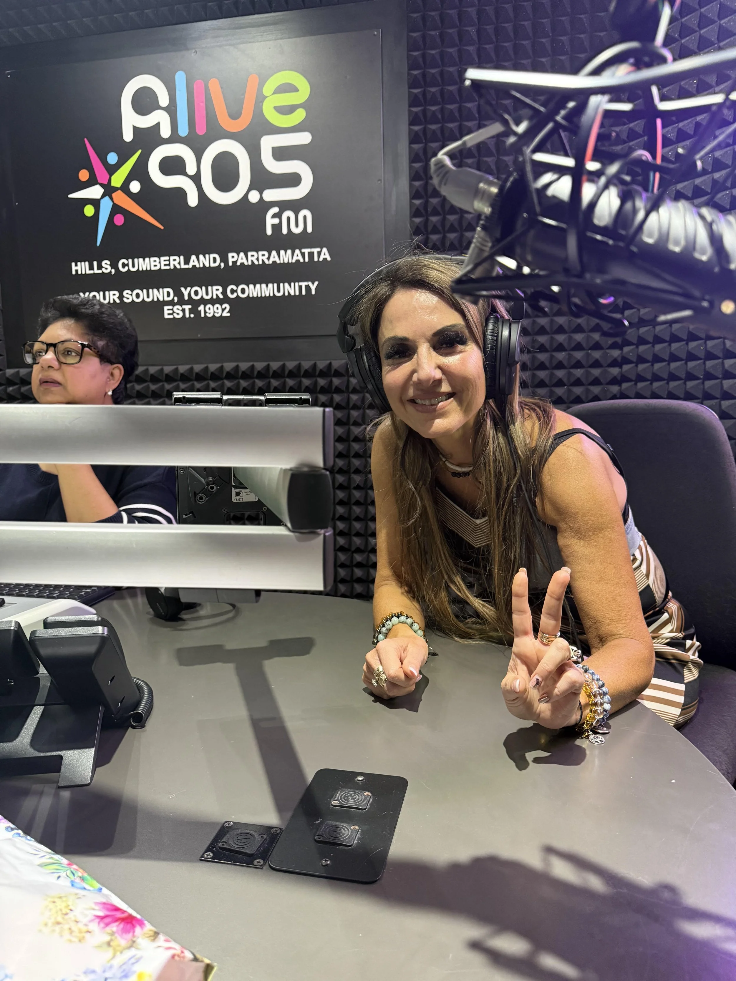 Woman speaking at a radio station, 2SER 0.5 FM radio station, indicating it serves Hills, Cumberland, and Parramatta, established in 1992.