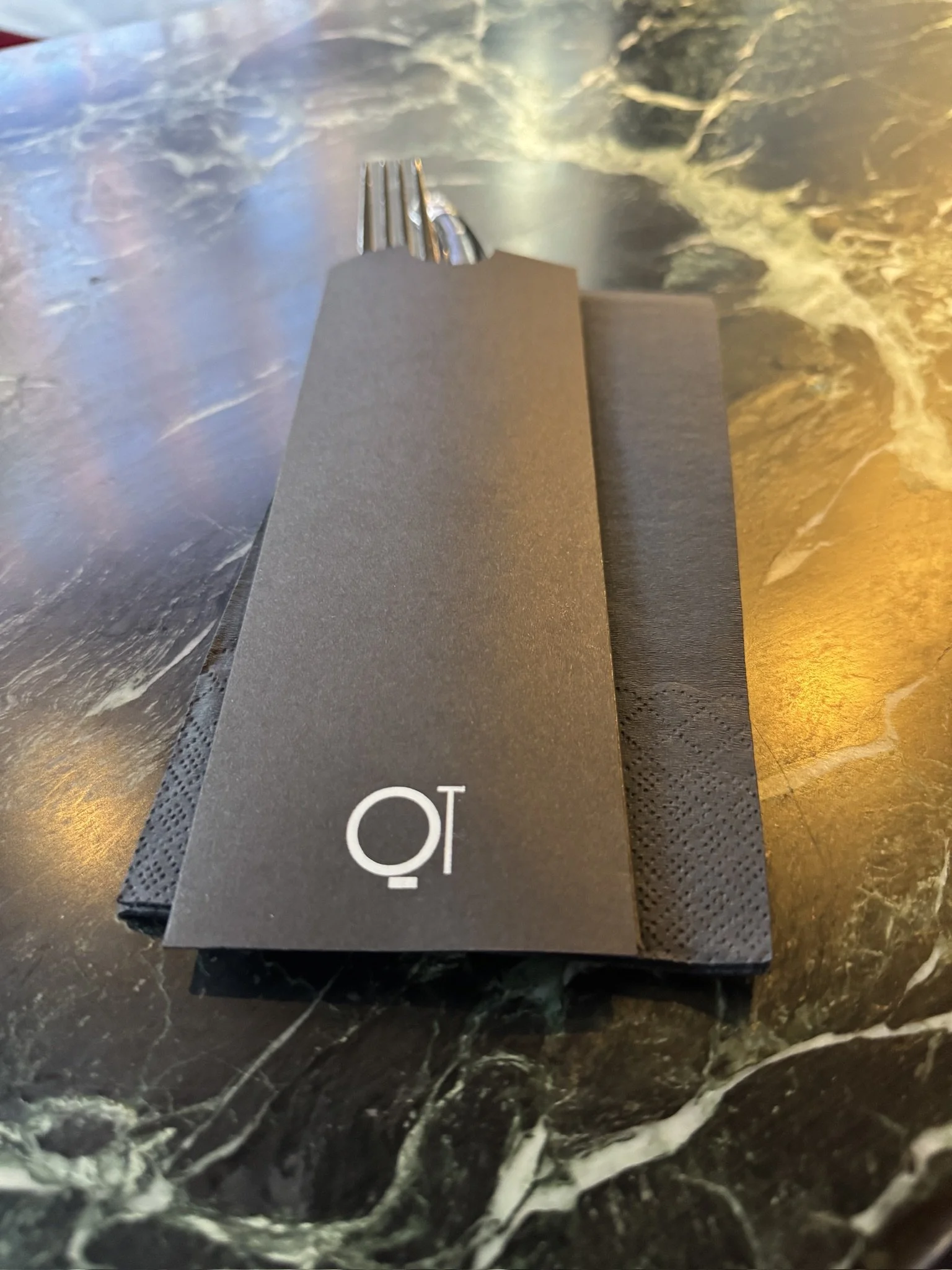 Close-up of a black marble surface with a black and gray paper object resting on it.