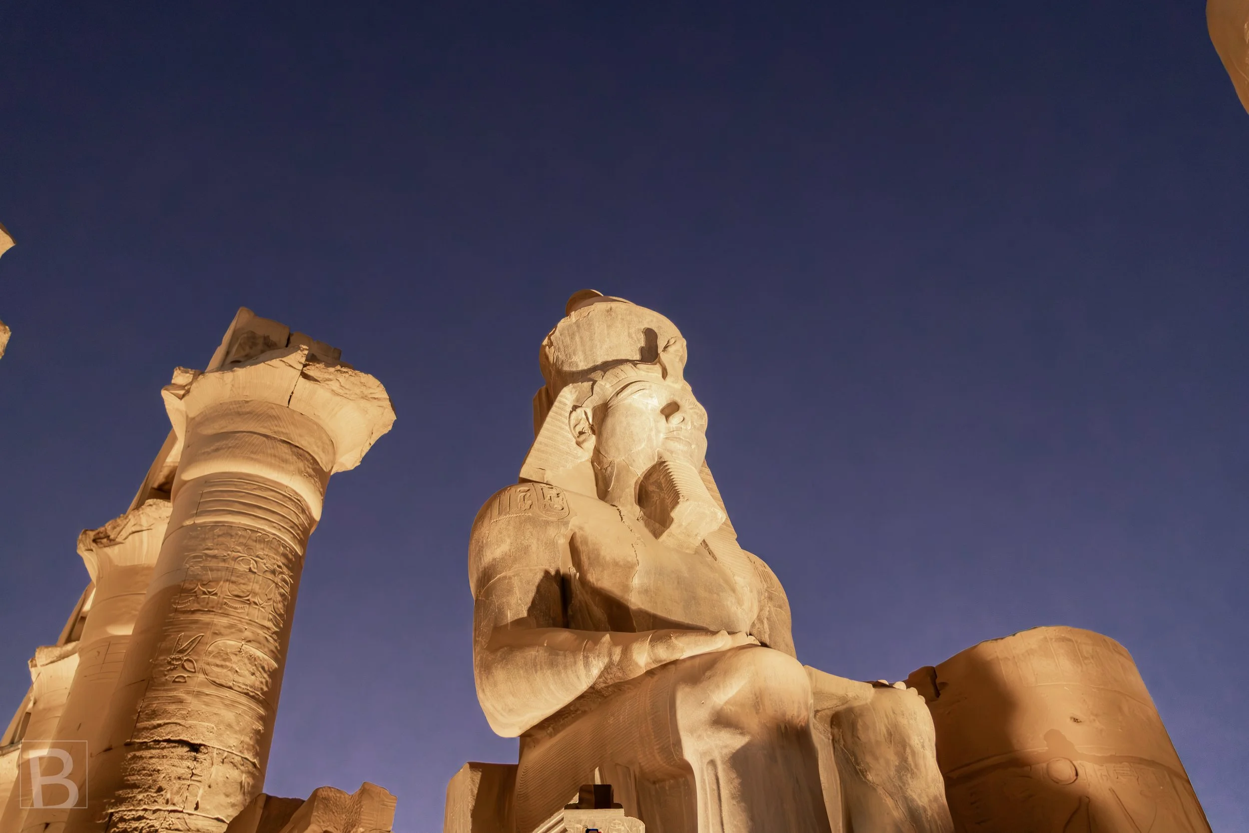 Against the black sky, the pharaoh's monumental figure commands
the entrance to Luxor Temple.
