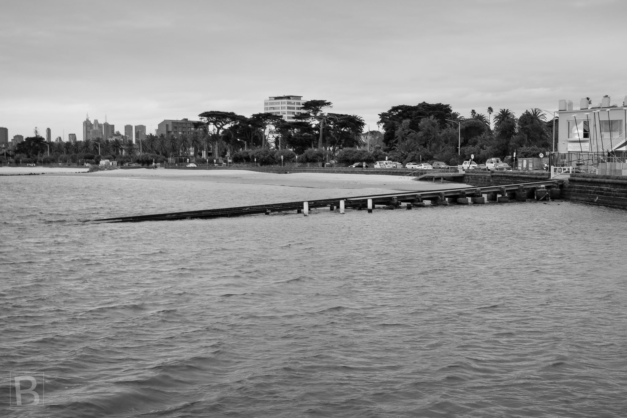 A simple line of timber and concrete reaches across open water,
connecting the quiet foreshore with the distant city.