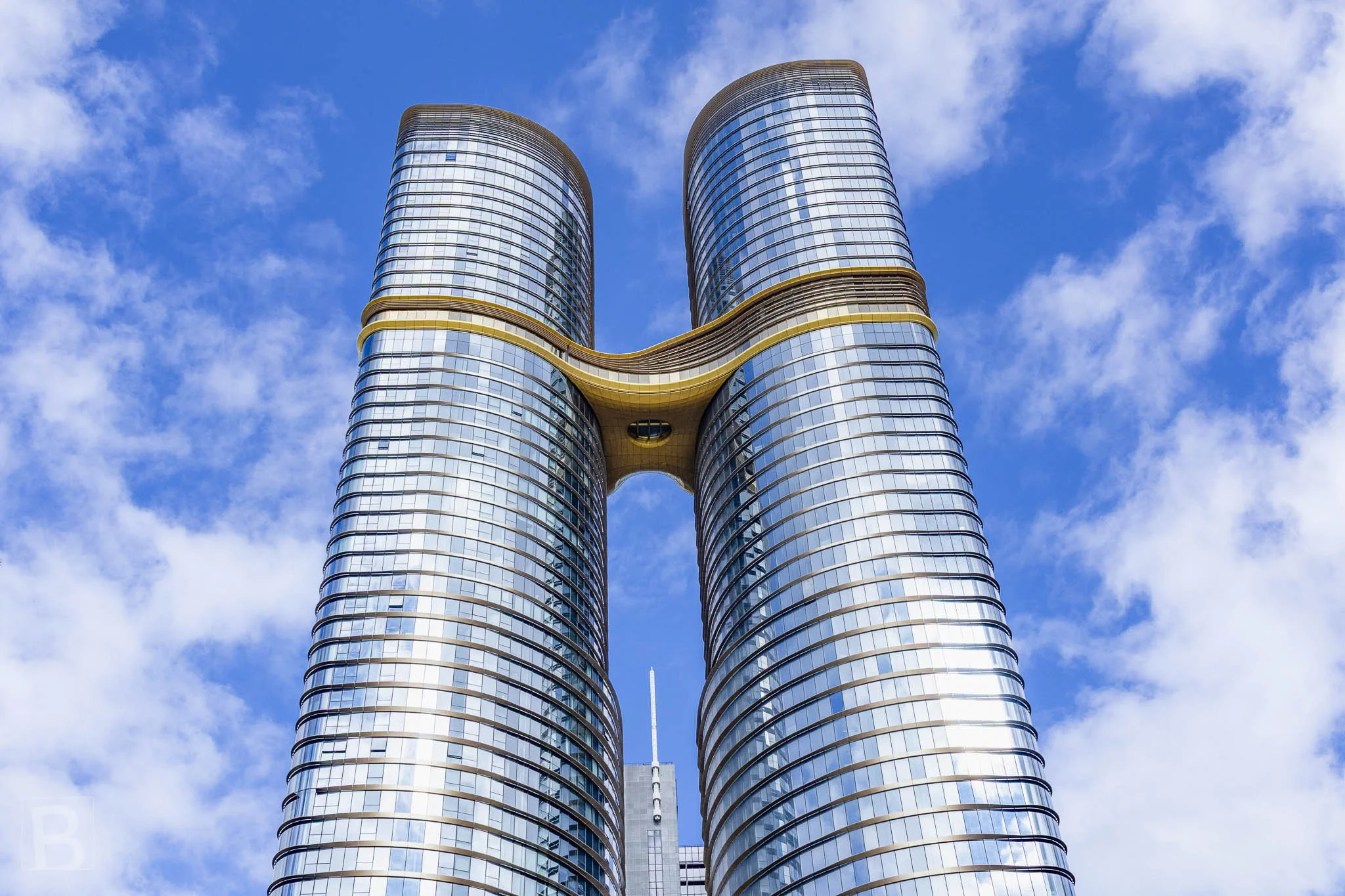 Reflective twin towers rise in parallel while a suspended bridge joins
them, combining vertical scale with an elegant structural connection.