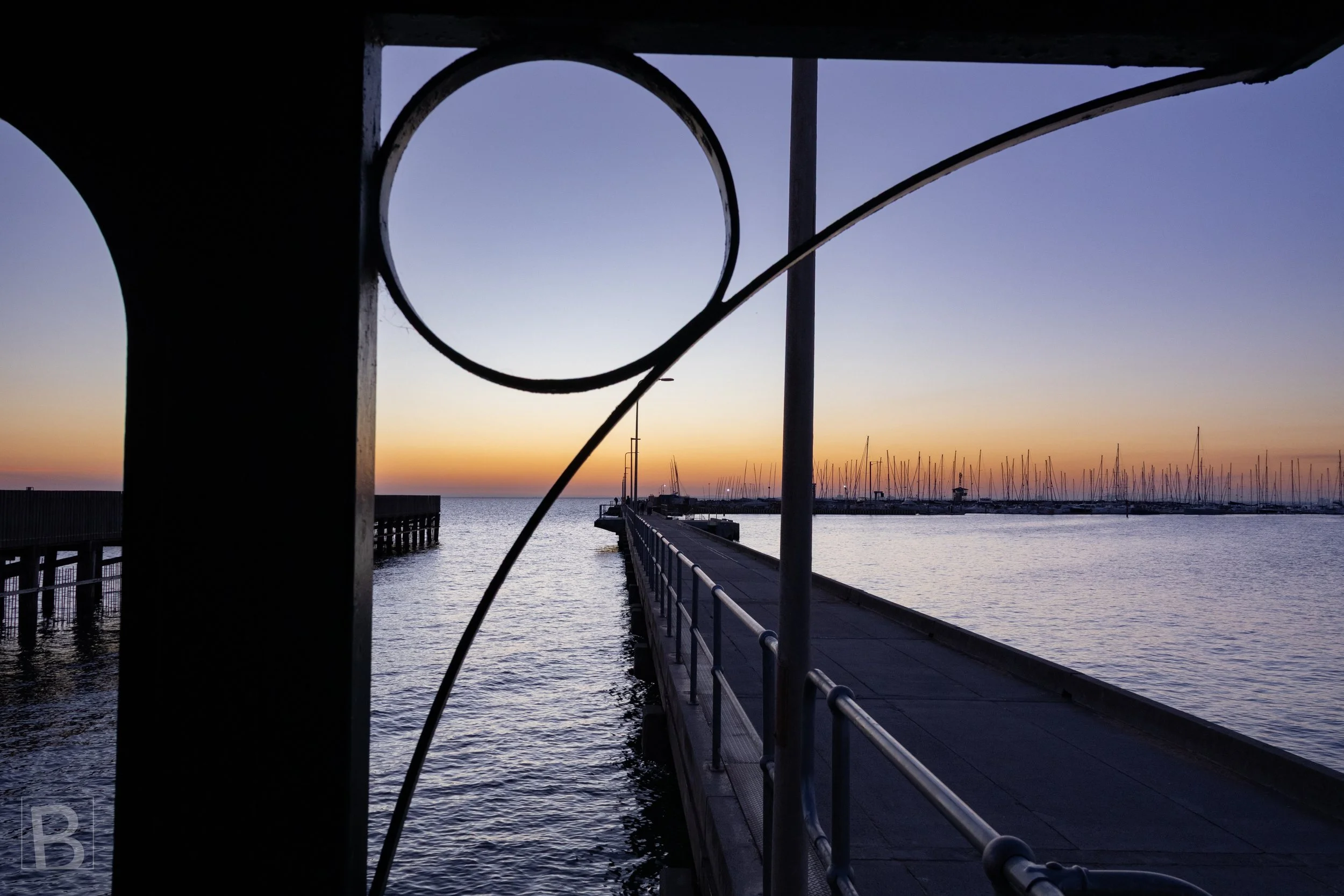 Sweeping stair rails create fluid geometry against a straight pier, still
water and the soft colour remaining after sunset.